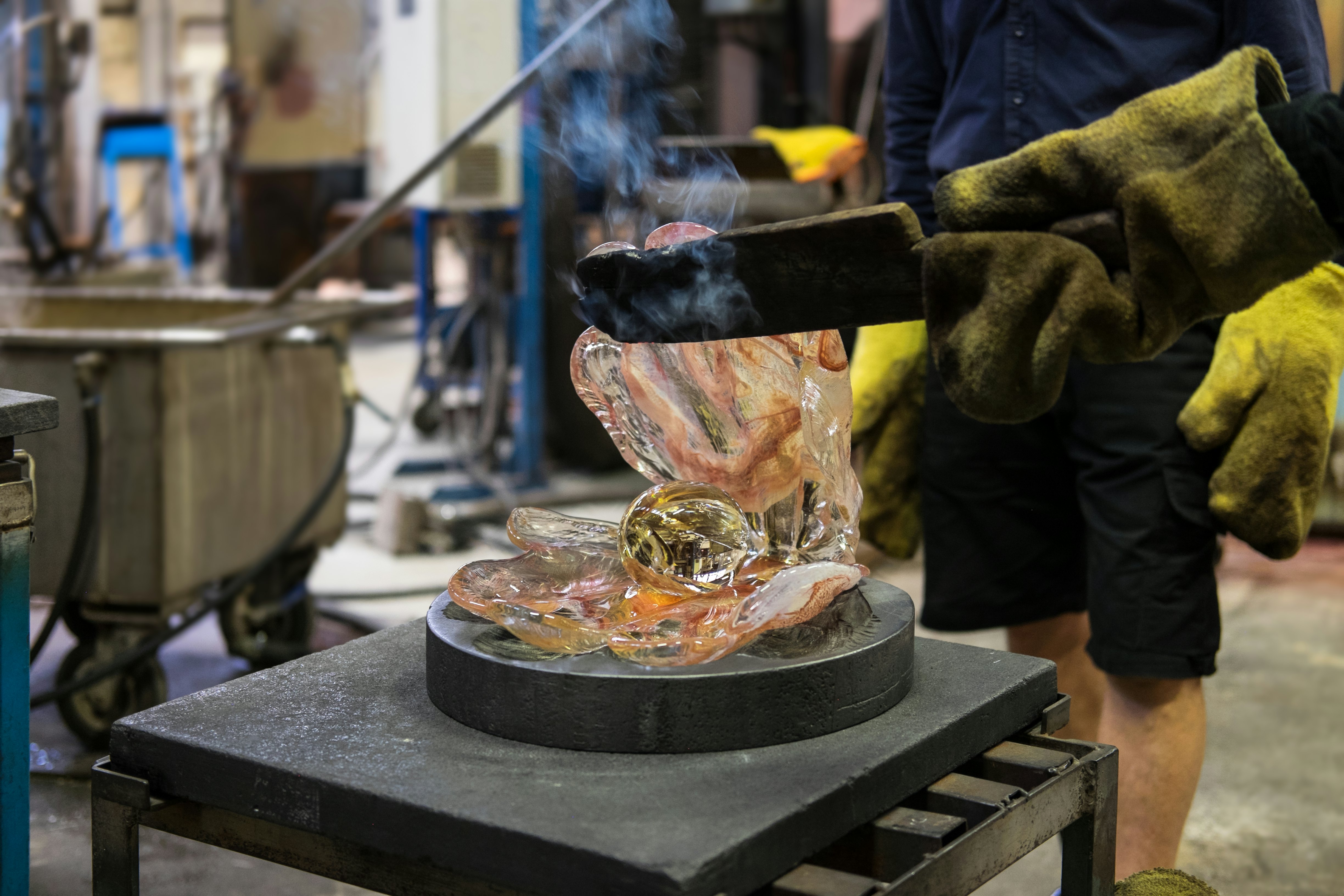 Making a glass shell with a pearl out of just blown liquid and glowing hot colored glass in Kosta glassworks in Sweden.