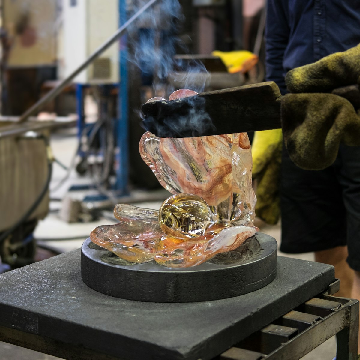 Making a glass shell with a pearl out of just blown liquid and glowing hot colored glass in Kosta glassworks in Sweden.