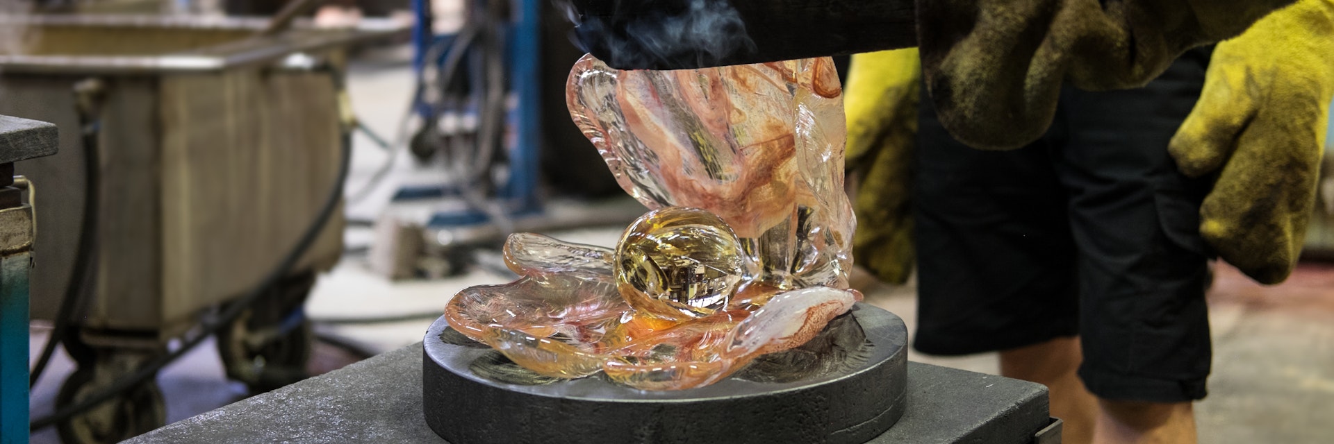 Making a glass shell with a pearl out of just blown liquid and glowing hot colored glass in Kosta glassworks in Sweden.