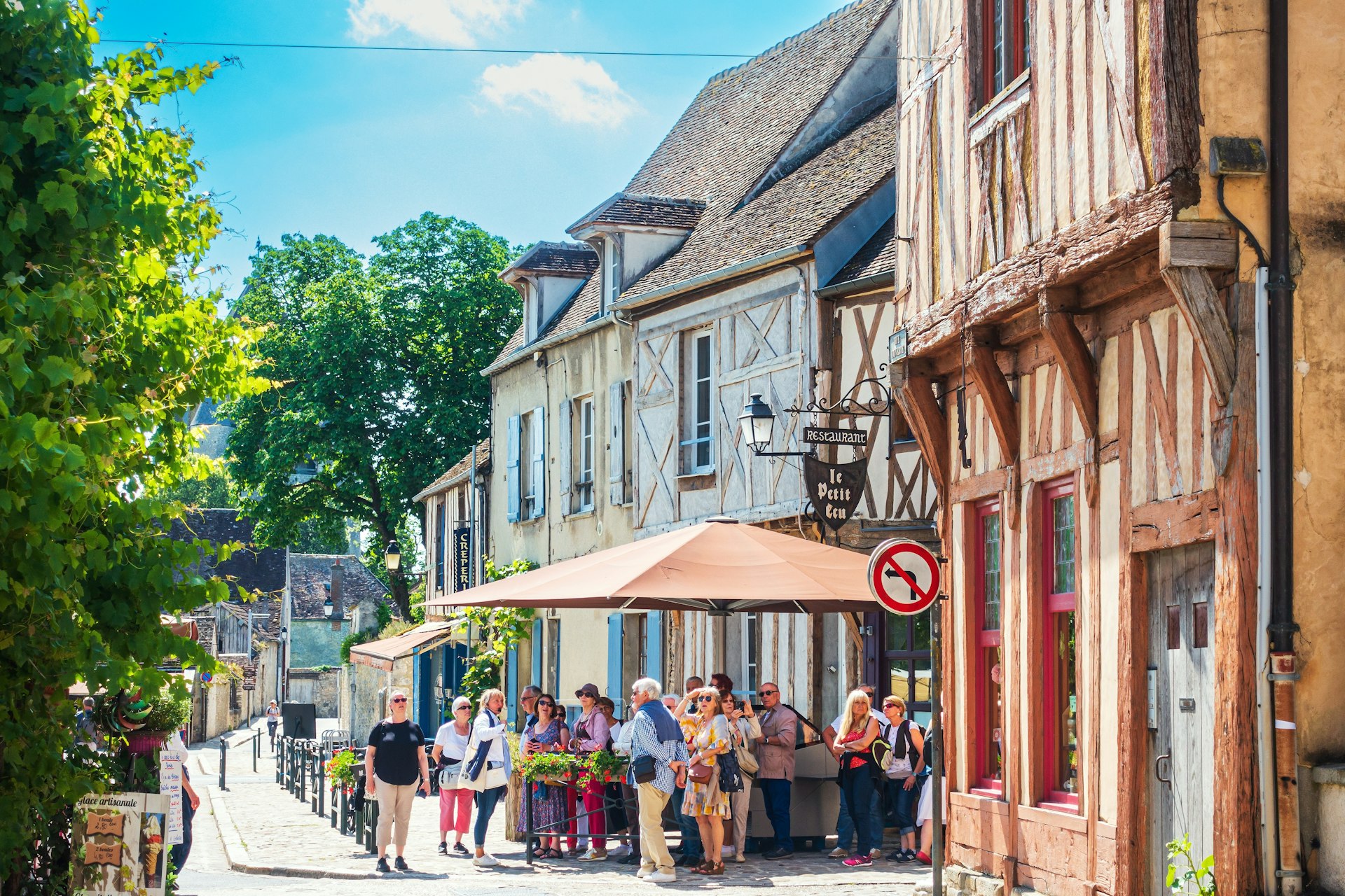 Tourists on foot on a pretty tree-lined street in Provins, France
