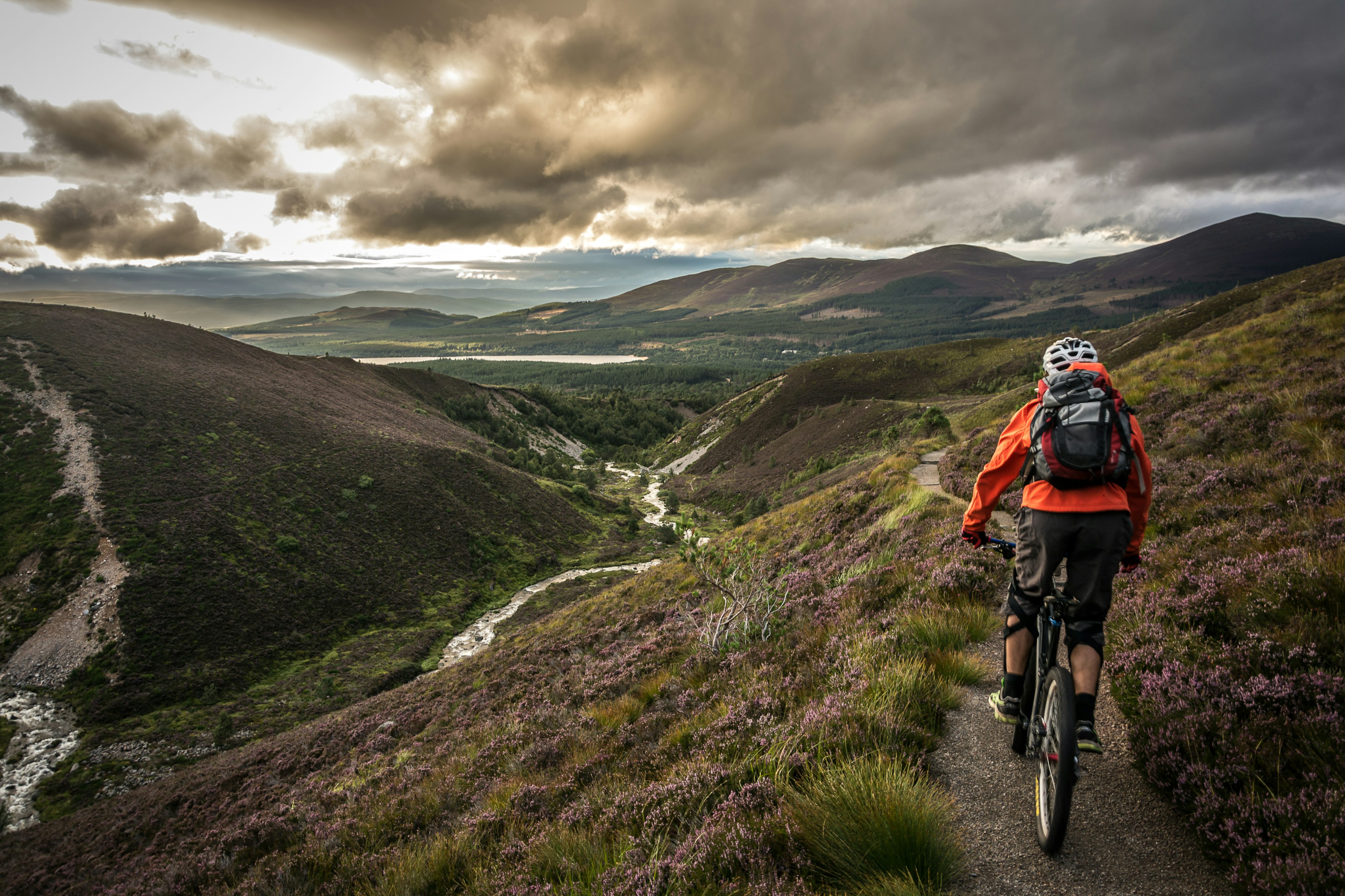 A young person on a mountain bike follows a trail in beautiful hilly countryside