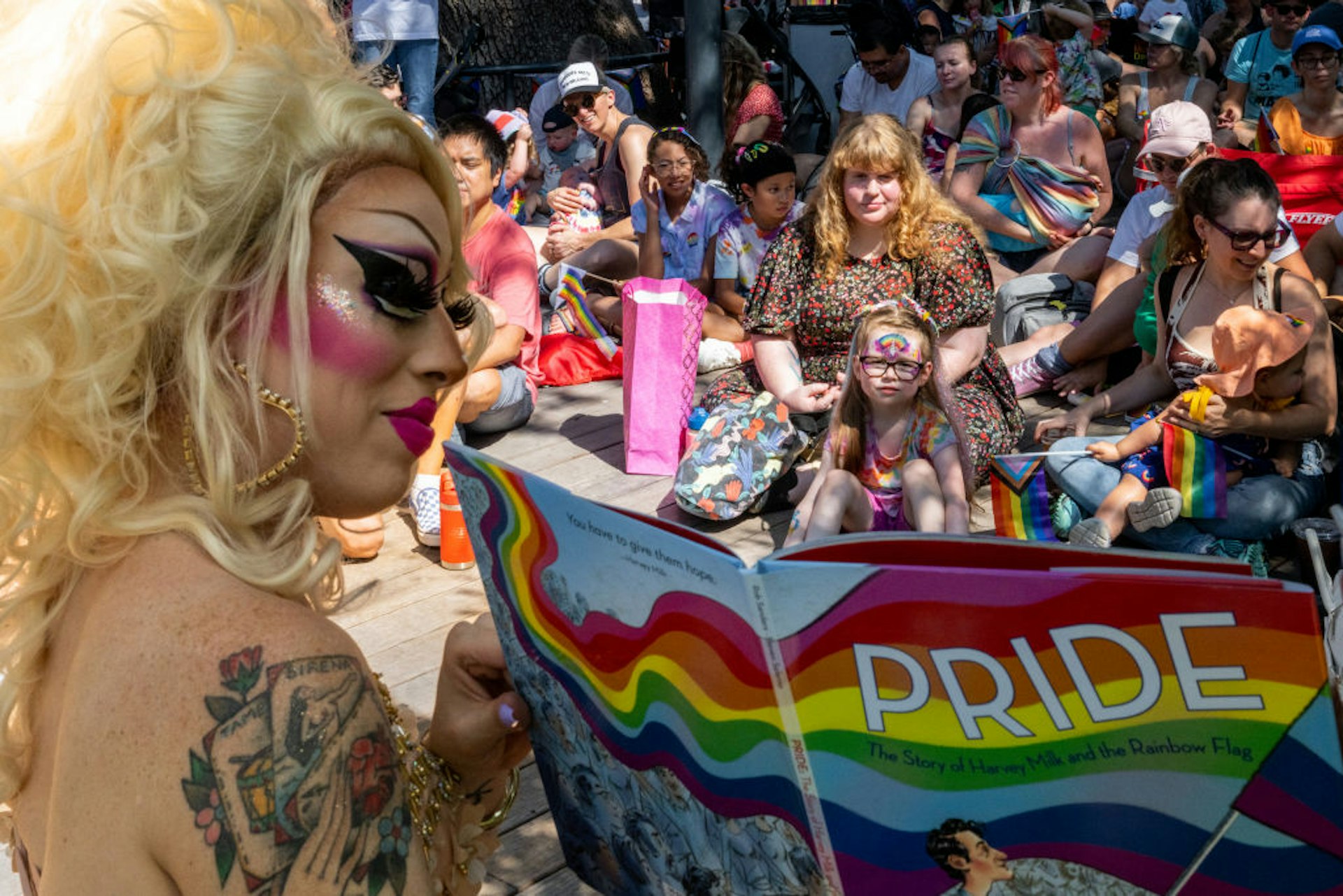 drag queen Brigitte Bandit reads a book during a drag time story hour at the Waterloo Greenway park