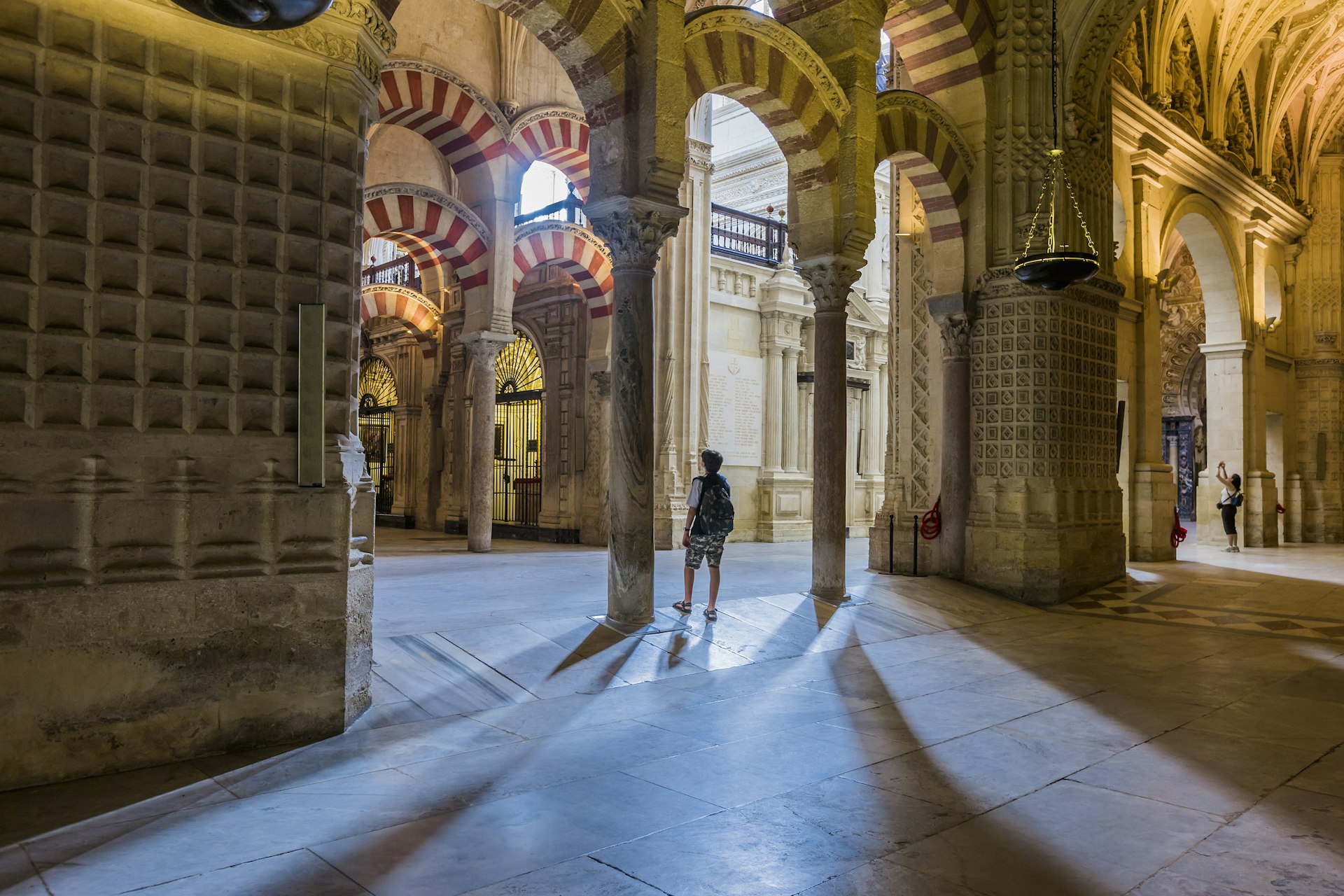 Un hombre con pantalones cortos y una camiseta admira la arquitectura de una mezquita.