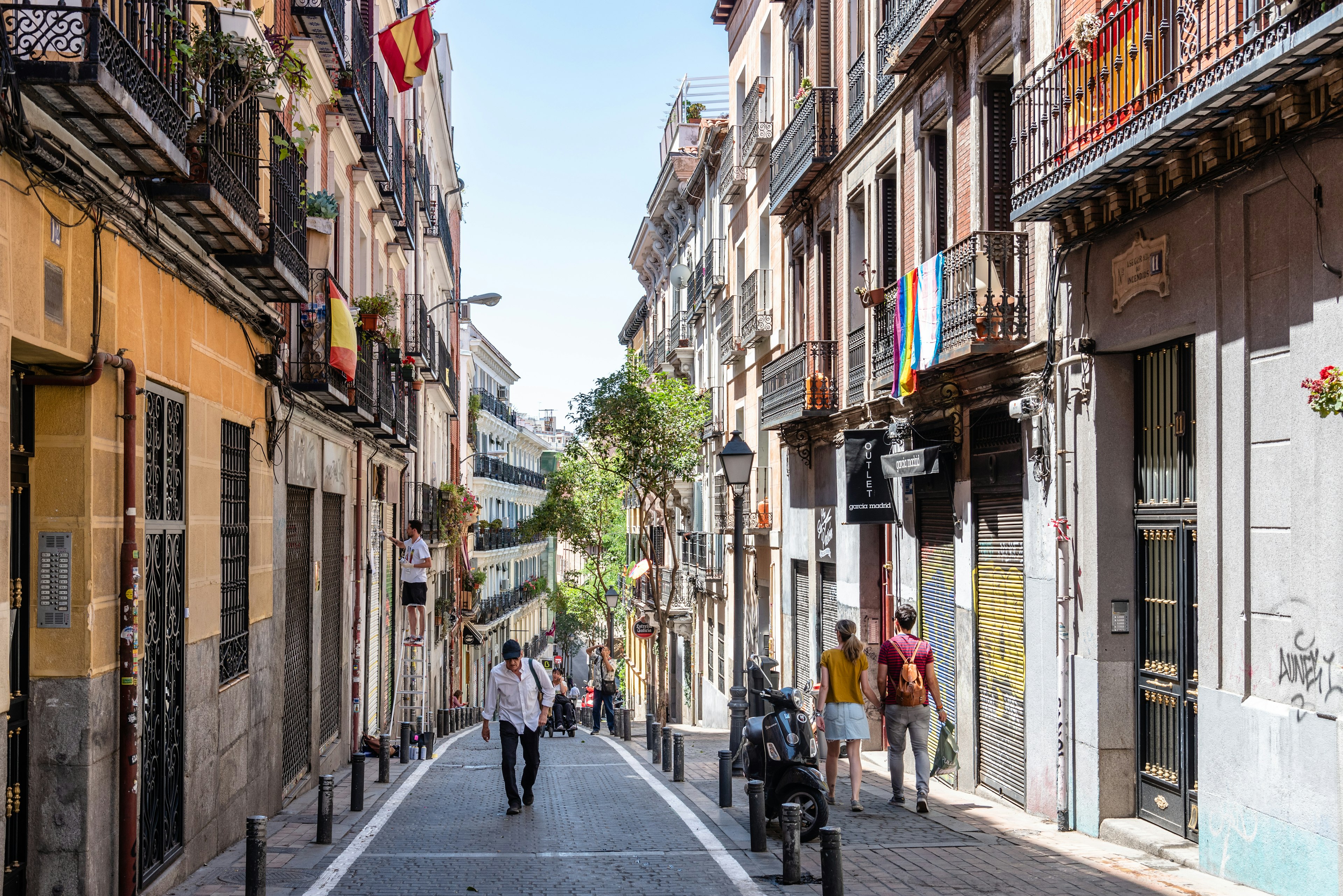 A narrow pedestrian street in Madrid, lined with cobblestones and old buildings