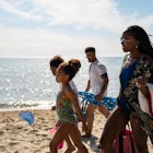 Children and their parents are walking on the beach and carrying parasol and other beach stuffs.
1157800361
A family with two kids walking along the beach in Greece together