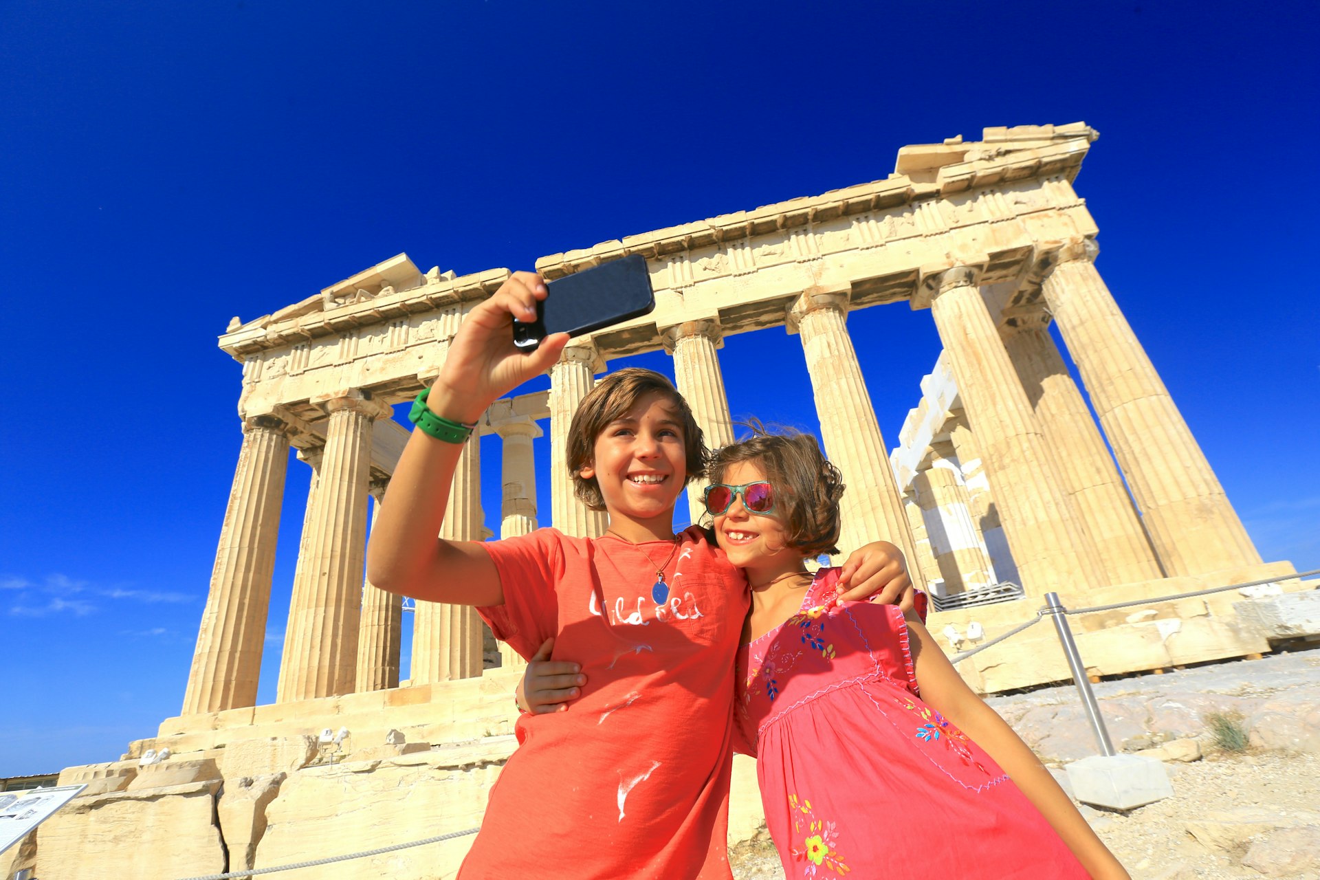 Two kids taking a selfie in front of the Parthenon in Athens