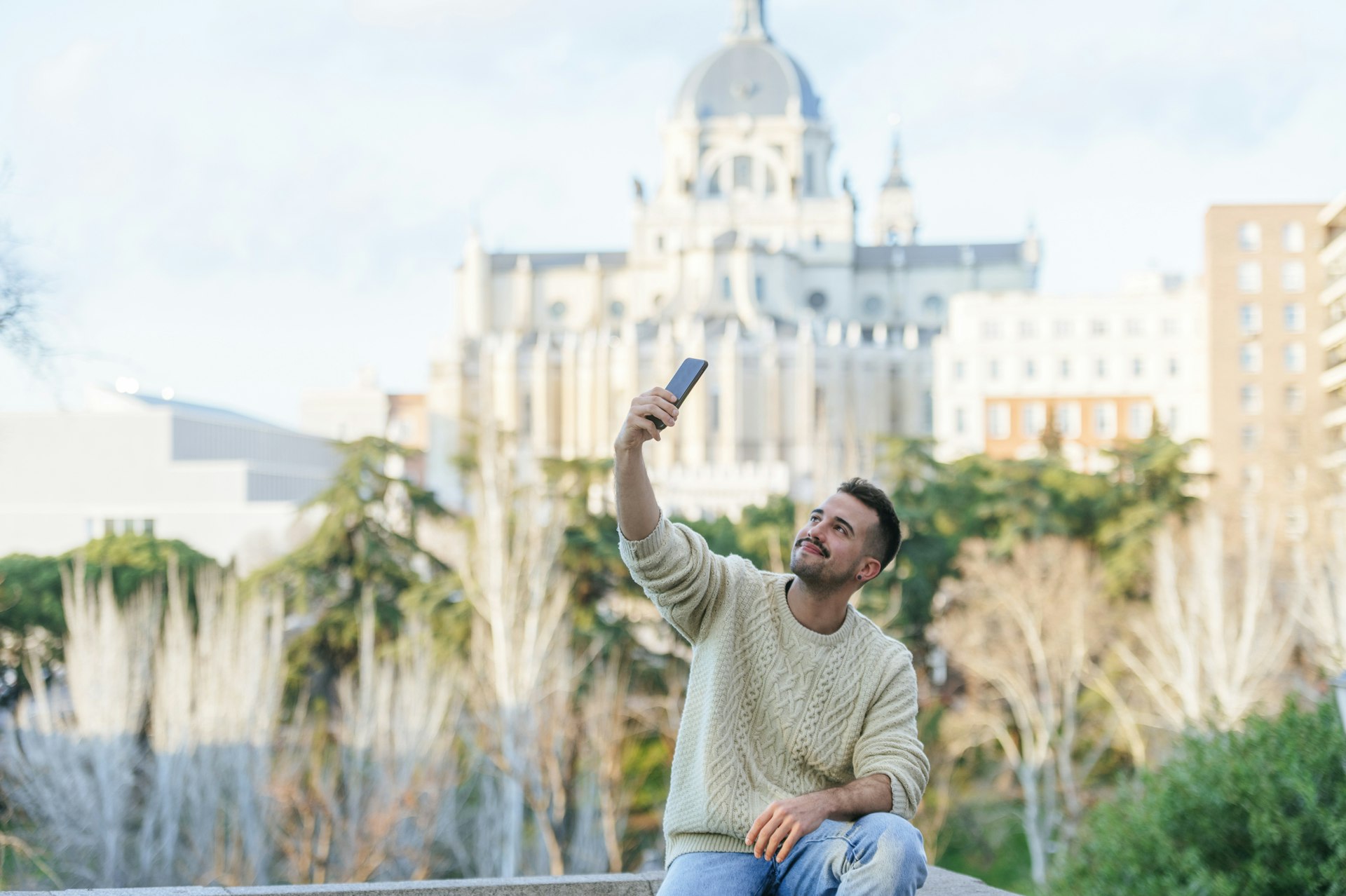 Man taking a selfie with the Almudena in the background, Madrid, Spain.