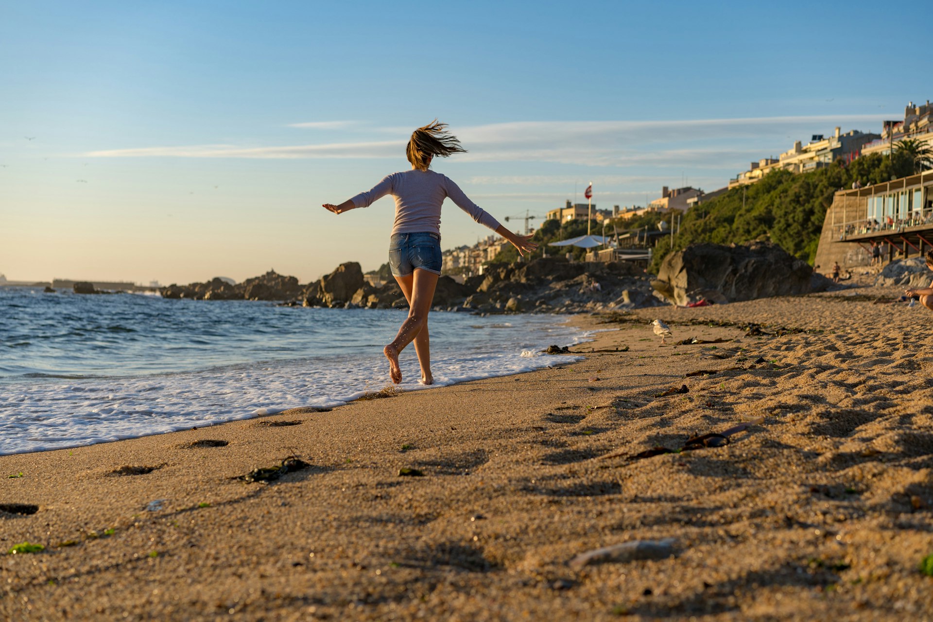 A young woman runs along a sandy beach on a sunny day