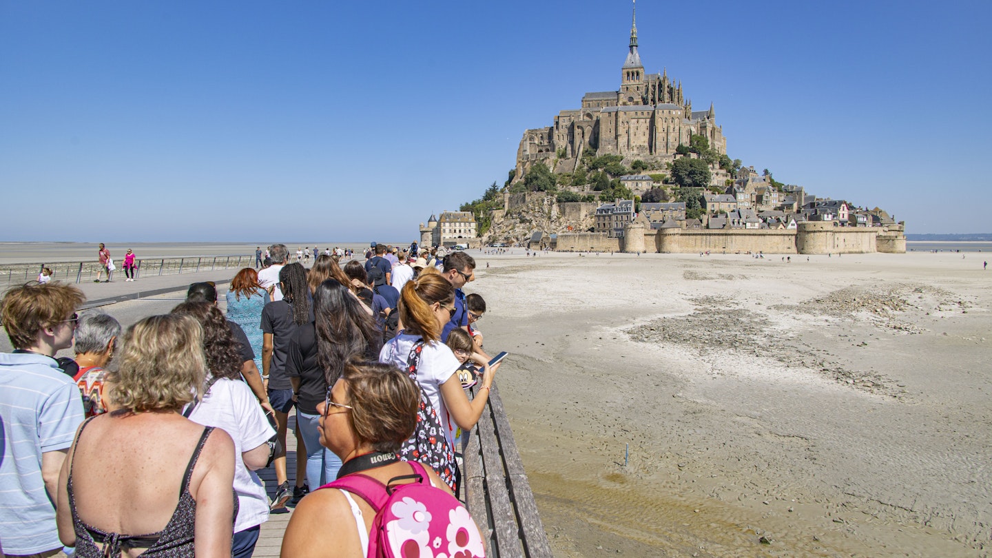 Lines of tourists and visitors waiting to board the bus towards the parking or arriving and walking towards the island. Mont-Saint-Michel tidal island with the magnificent medieval monastic buildings and the Abbey of Saint Michel with the statue of Archangel Michael atop the spire, in Normandy, France. Le Mont Saint Michel is a UNESCO World Heritage Site since 1979 and second most visited monument in France. The holy island with its breathtaking bay is a major Christian pilgrimage site destination for Europe for centuries. The Mont-Saint-Michel is one of Europes most unforgettable sights. July 2022 (Photo by Nicolas Economou/NurPhoto via Getty Images)
1242376118
brittany, world heritage, religious, wall, destinations, exterior, world, bridge, st michel, crowd, panorama, reflections, saint michel, vacation, site, attraction, michael, fortification, mont saint michel, mont st michel, historical, building, gothic, walled, landscape, bretagne, famous, unesco, mont-saint-michel, fortress