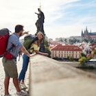 Tourist couple sightseeing in Prague; Traveller lifestyle
1301247480
A man and woman wearing backpacks standing on a bridge in Prague in the sunshine