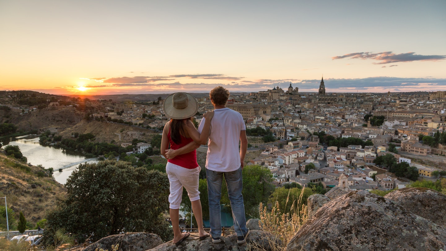 Spain, Castile La Mancha, Toledo. Adult couple of tourists looking at the city at sunset from a lookout 1364380908