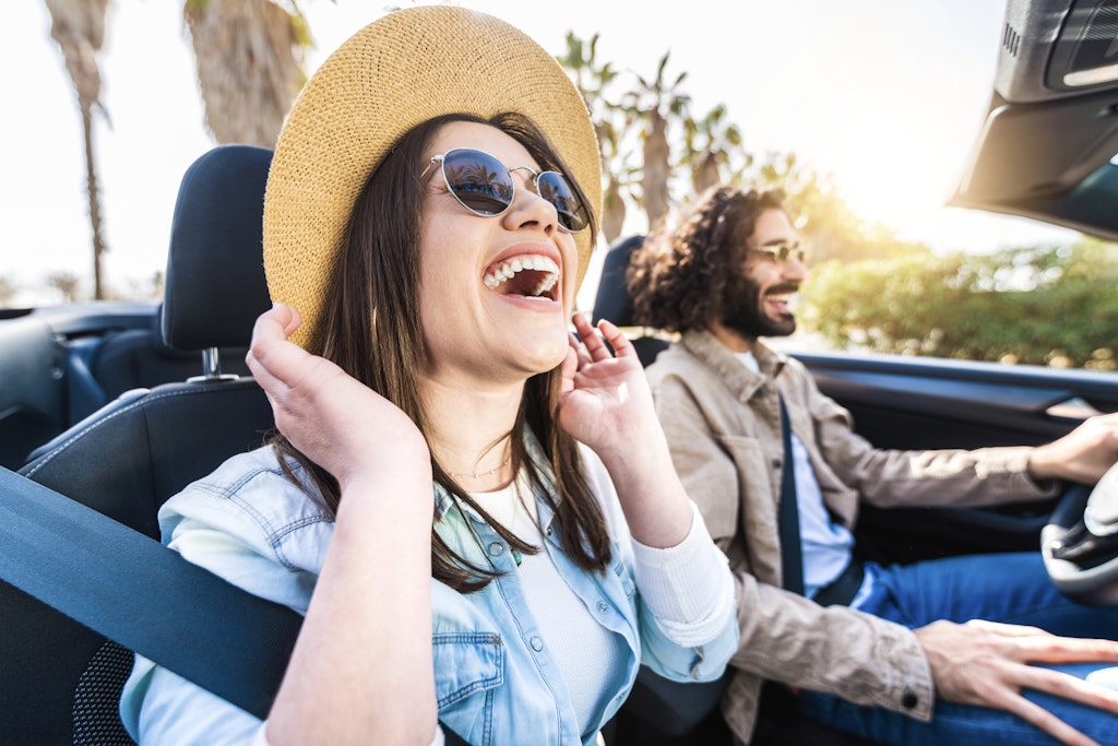 Happy couple driving convertible car enjoying summer vacation - Friends rent cabrio auto on holiday - Roadtrip, freedom, travel and transport rental service concept
1384618163
A smiling laughing couple driving a car in Spain
