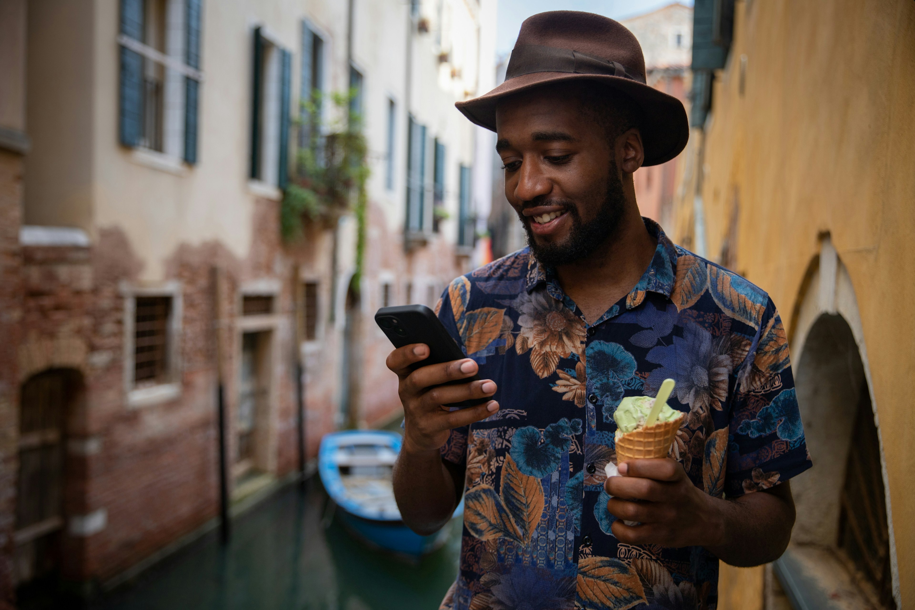 A man with an ice cream in one hand and his phone in the other on a bridge in Venice