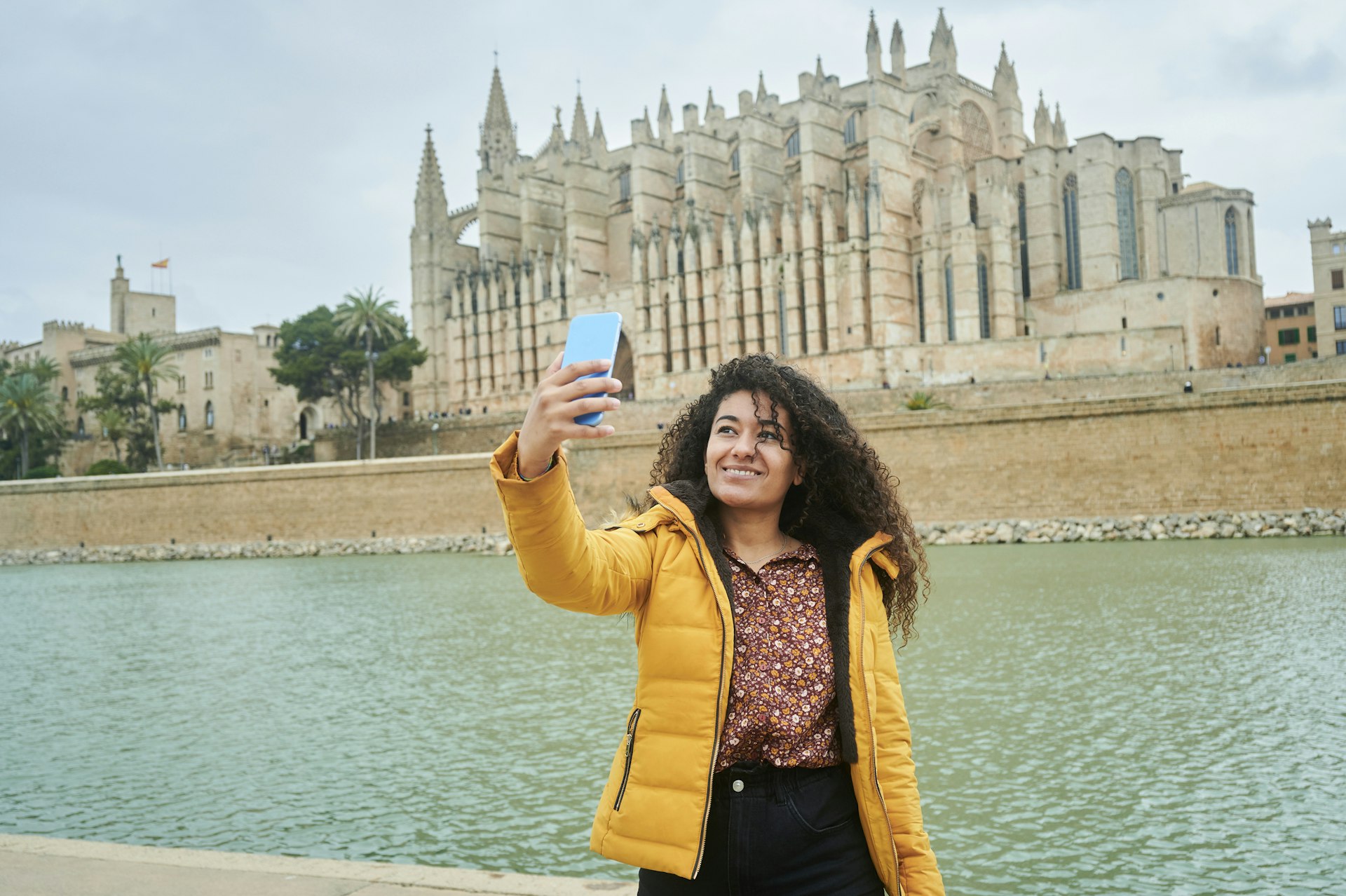 Woman taking a selfie in front of the cathedral of Palma de Mayorca, Balearic Islands, Spain