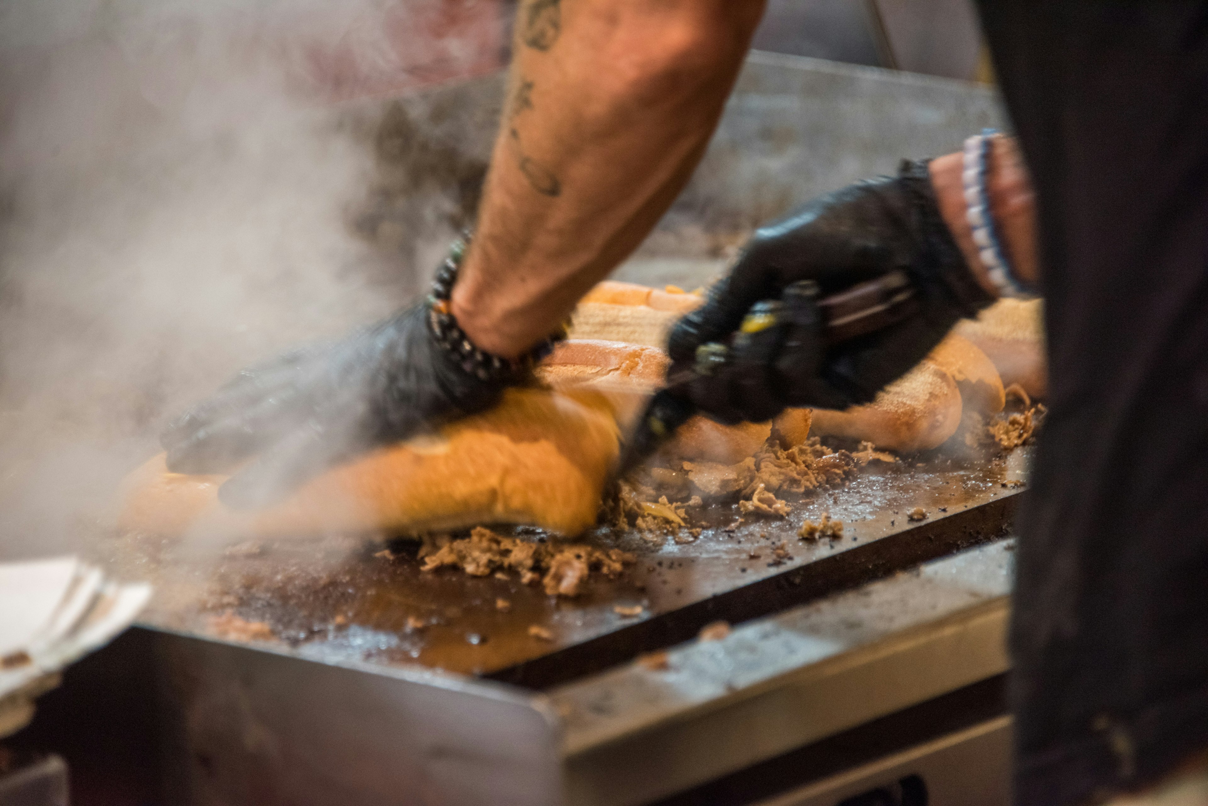 Thinly sliced rib-eye steak being cooked on a griddle to prepare Philly cheesesteak