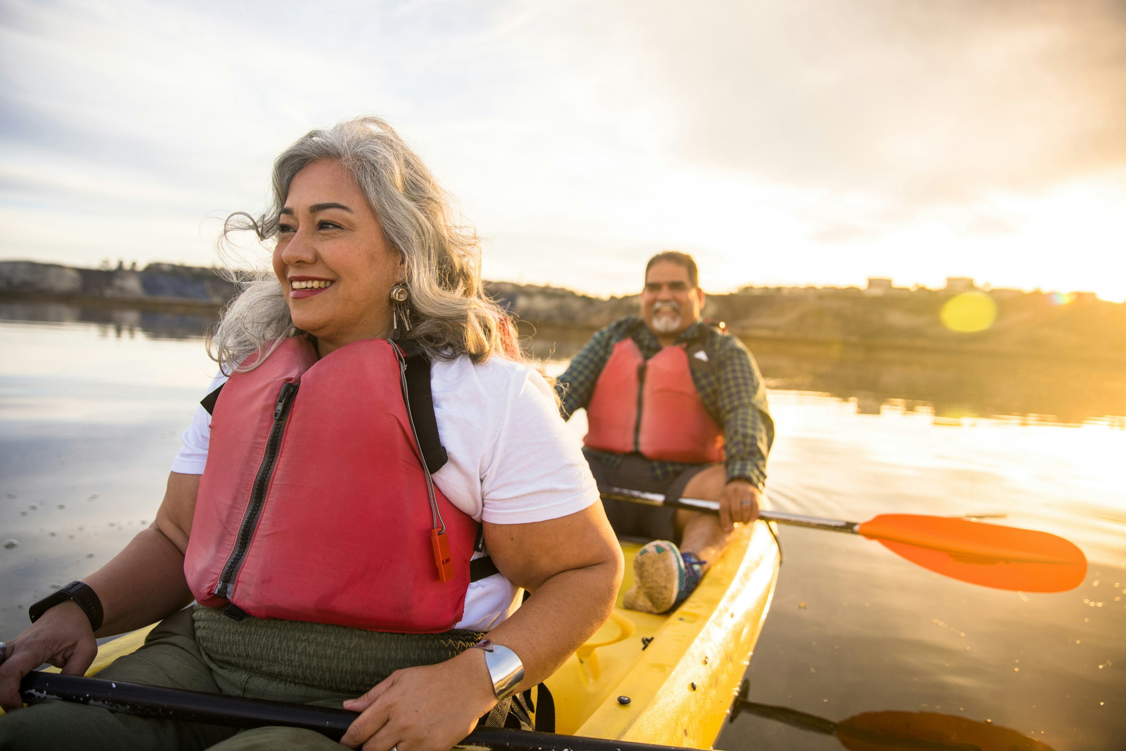 A senior couple kayaking in a double kayak at sunset