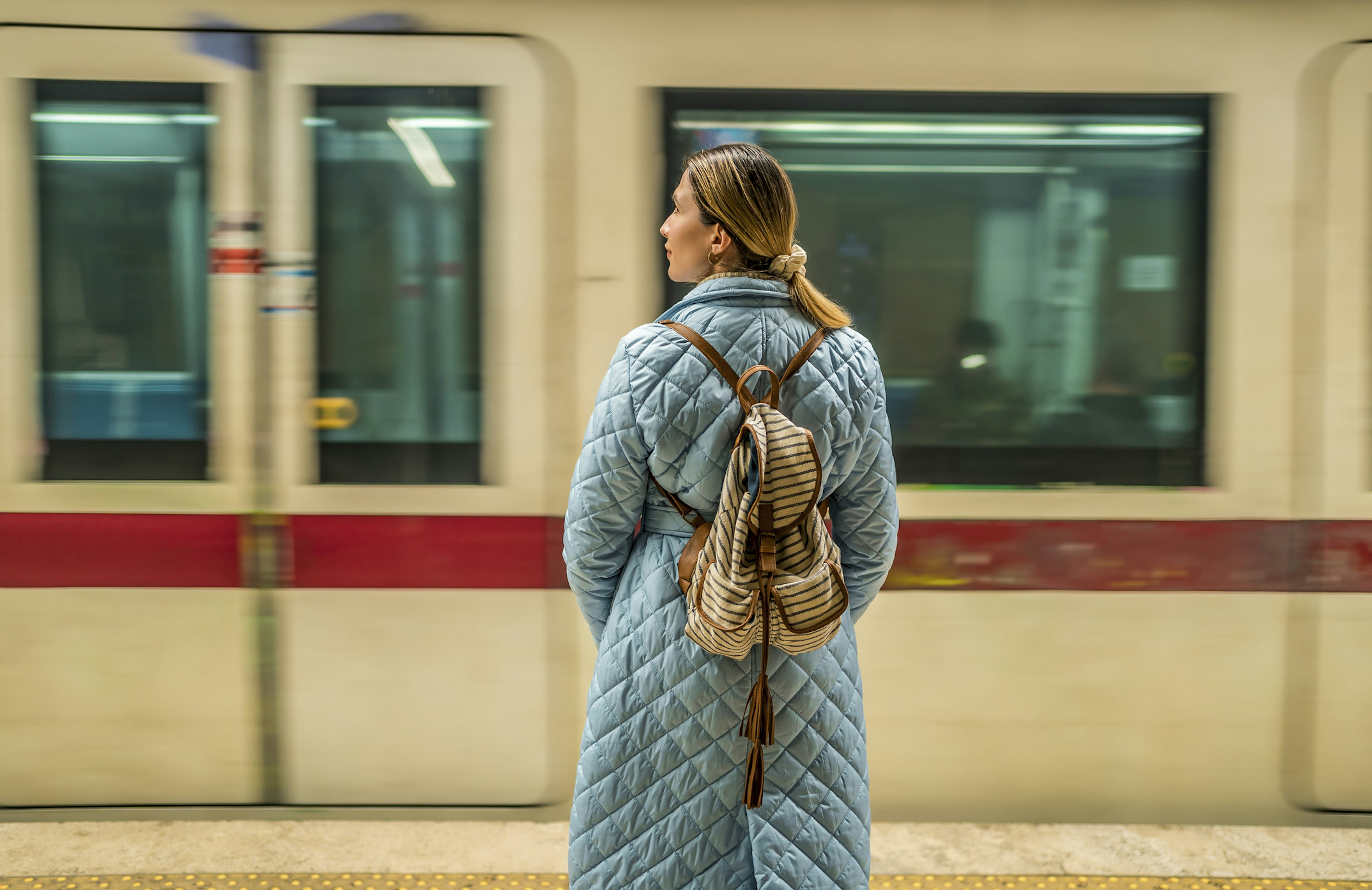 Young woman standing in a subway station while waiting for her subway