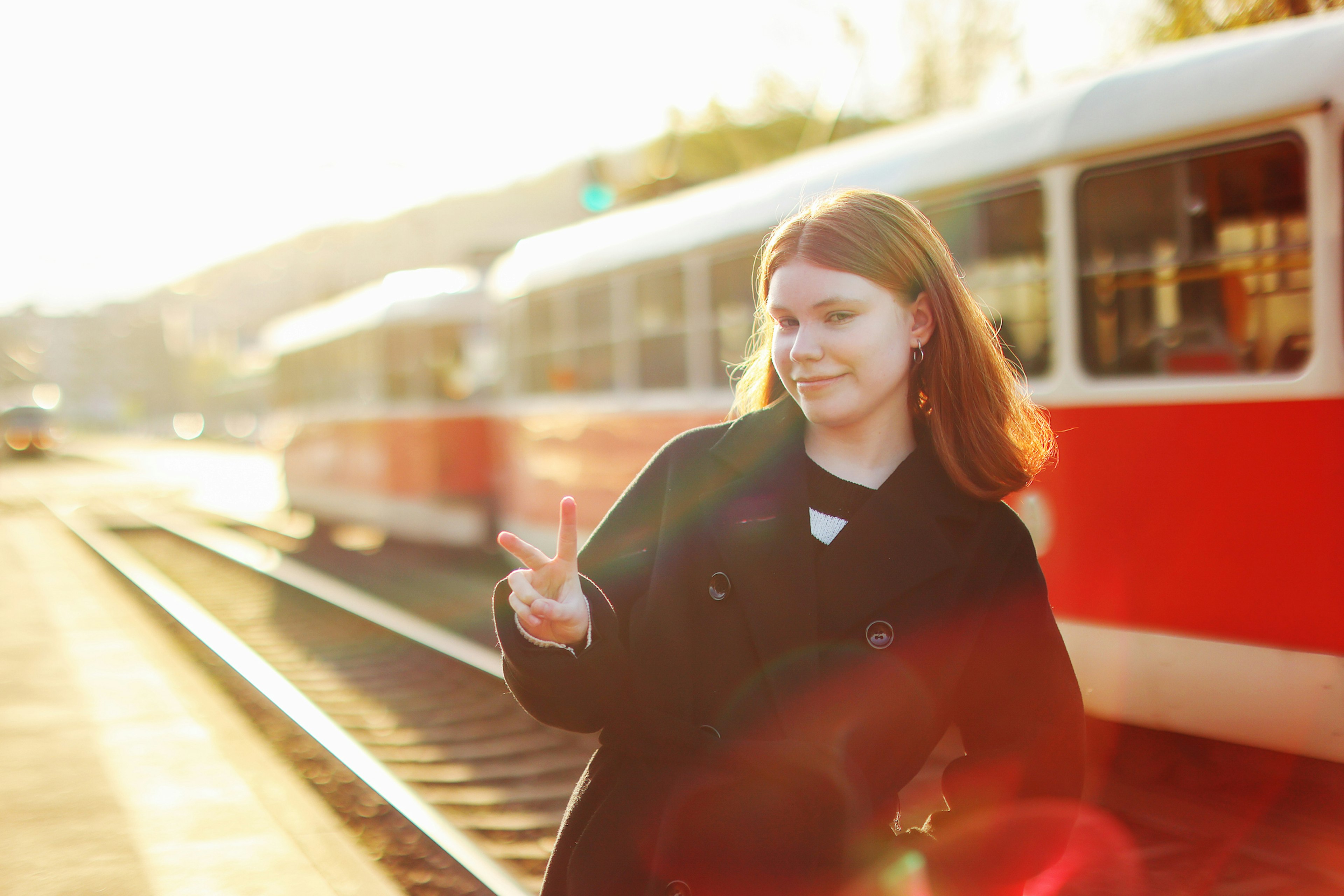 Teen girl stands before the old style tram and show good by hand