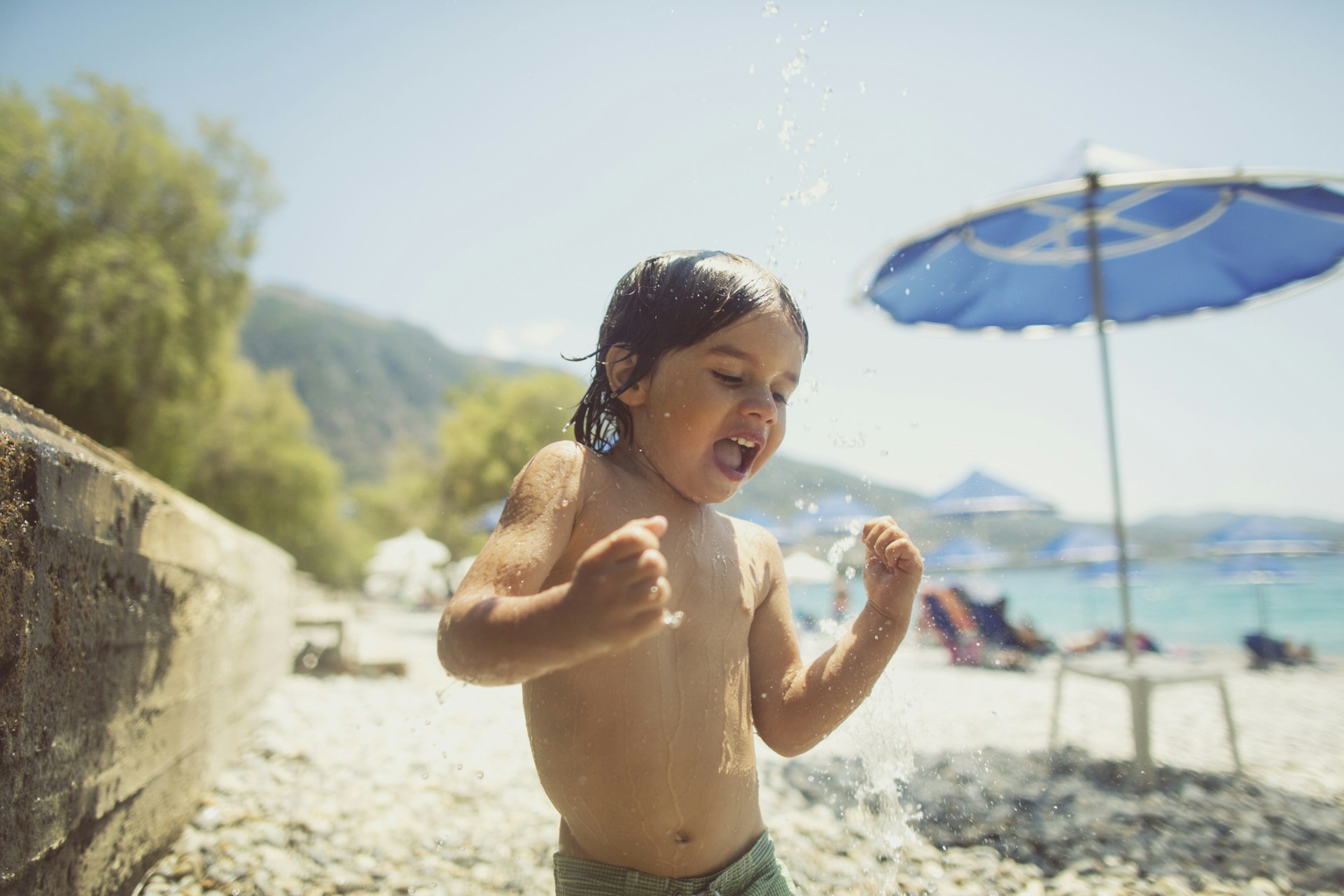 A small boy washing sand off on the beach in Greece