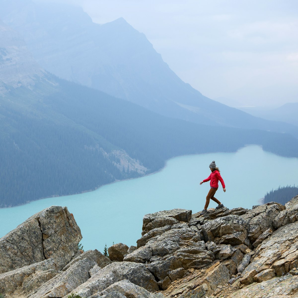 A woman hiking above a vibrant turquoise lake in Banff National Park.