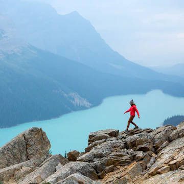 A woman hiking above a vibrant turquoise lake in Banff National Park.