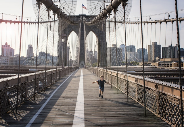 Boy running on Brooklyn Bridge, New York City