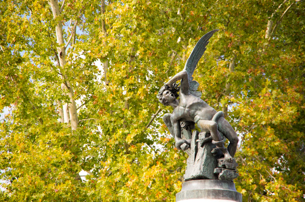 A statue of an angel in distress as demons surround it