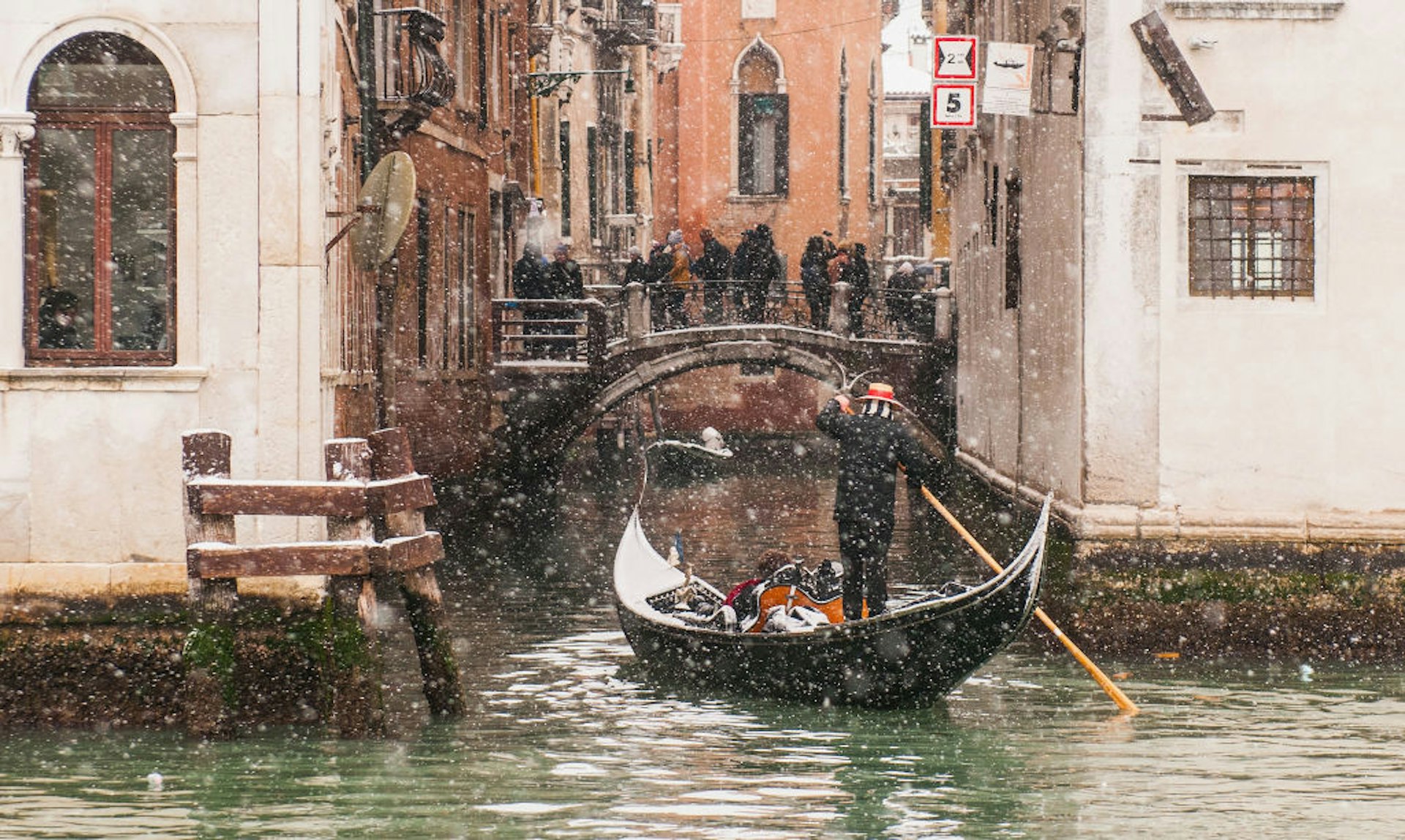 A gondola enters a canal during snowfall in Venice, Italy