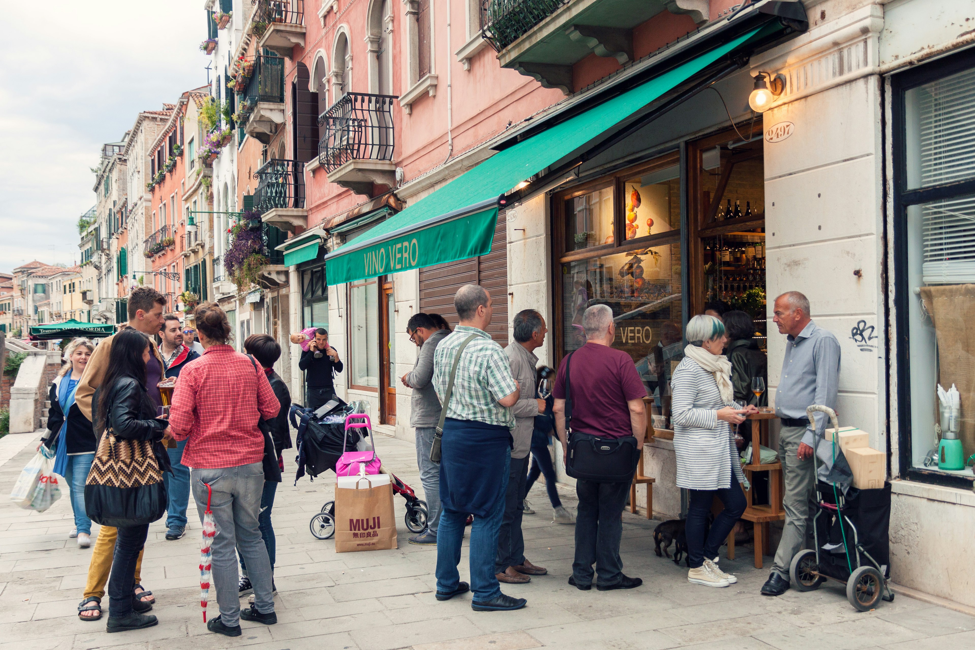 Crowd of people drinking and talking on the street outside wine bar in Venice, Italy