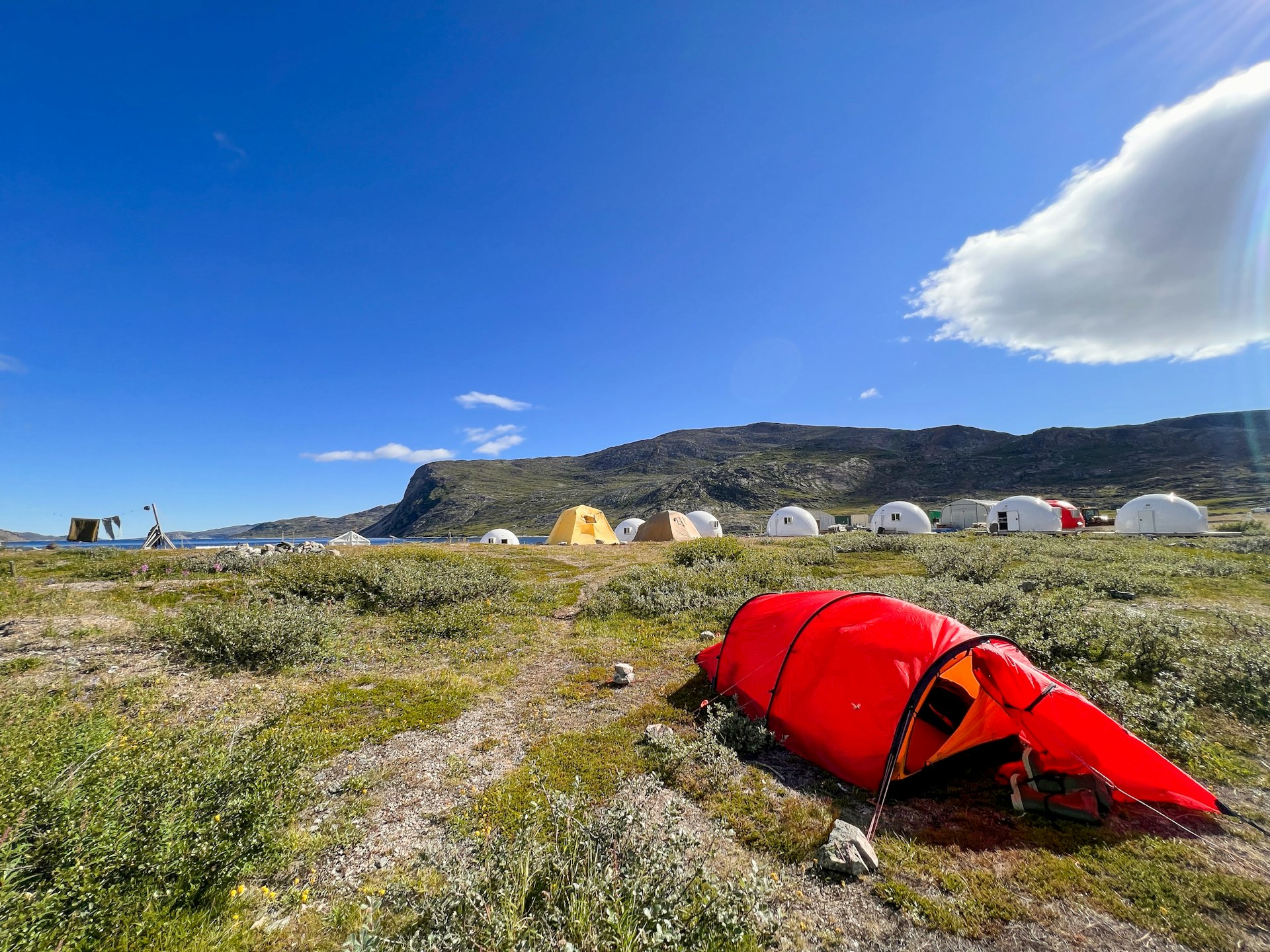 A remote campsite with a red tent in the foreground