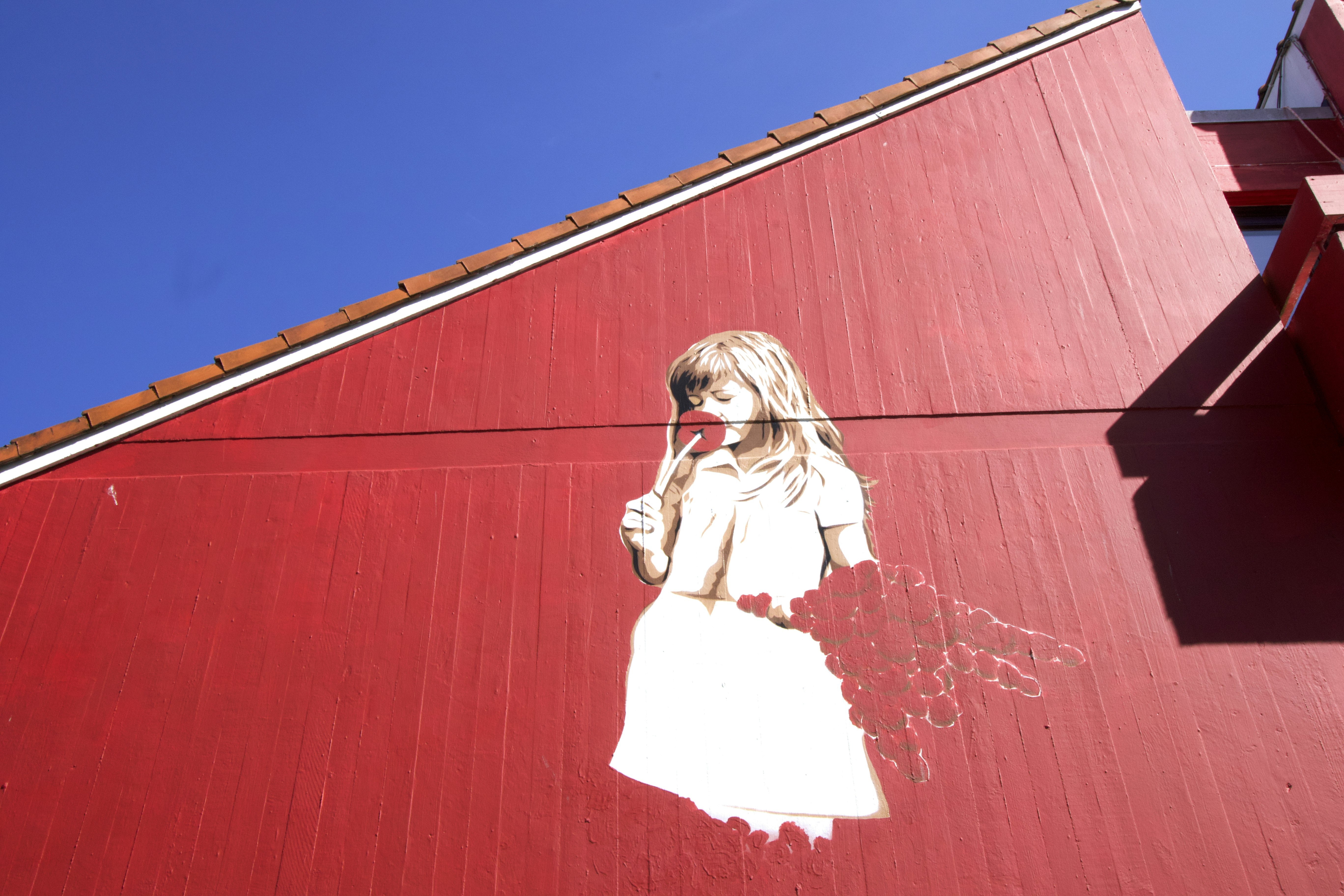 Stavanger street art mural of a young girl in a white dress painted on a red wall