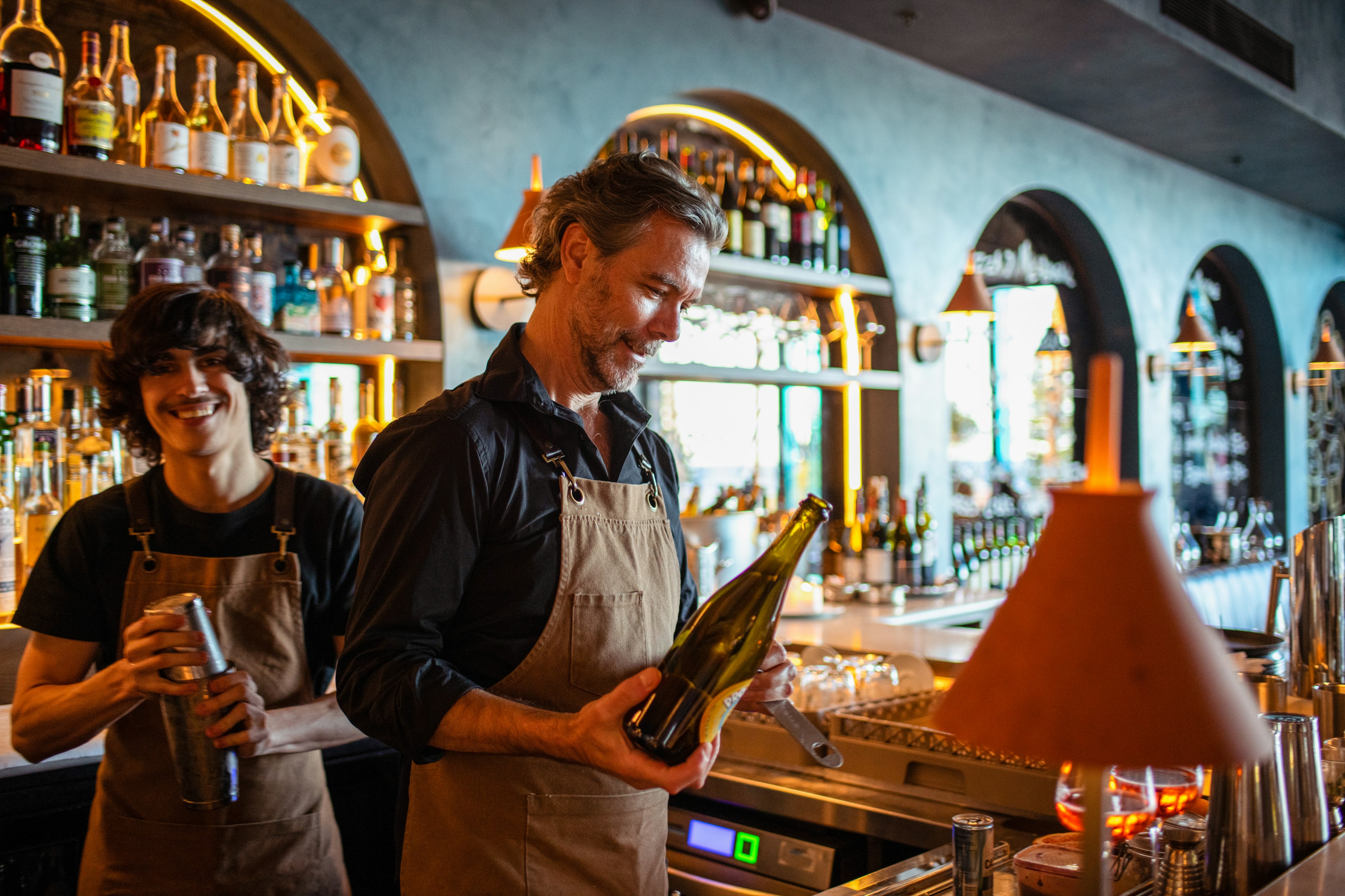 Two men working in a bar in Sydney one is pouring a drink