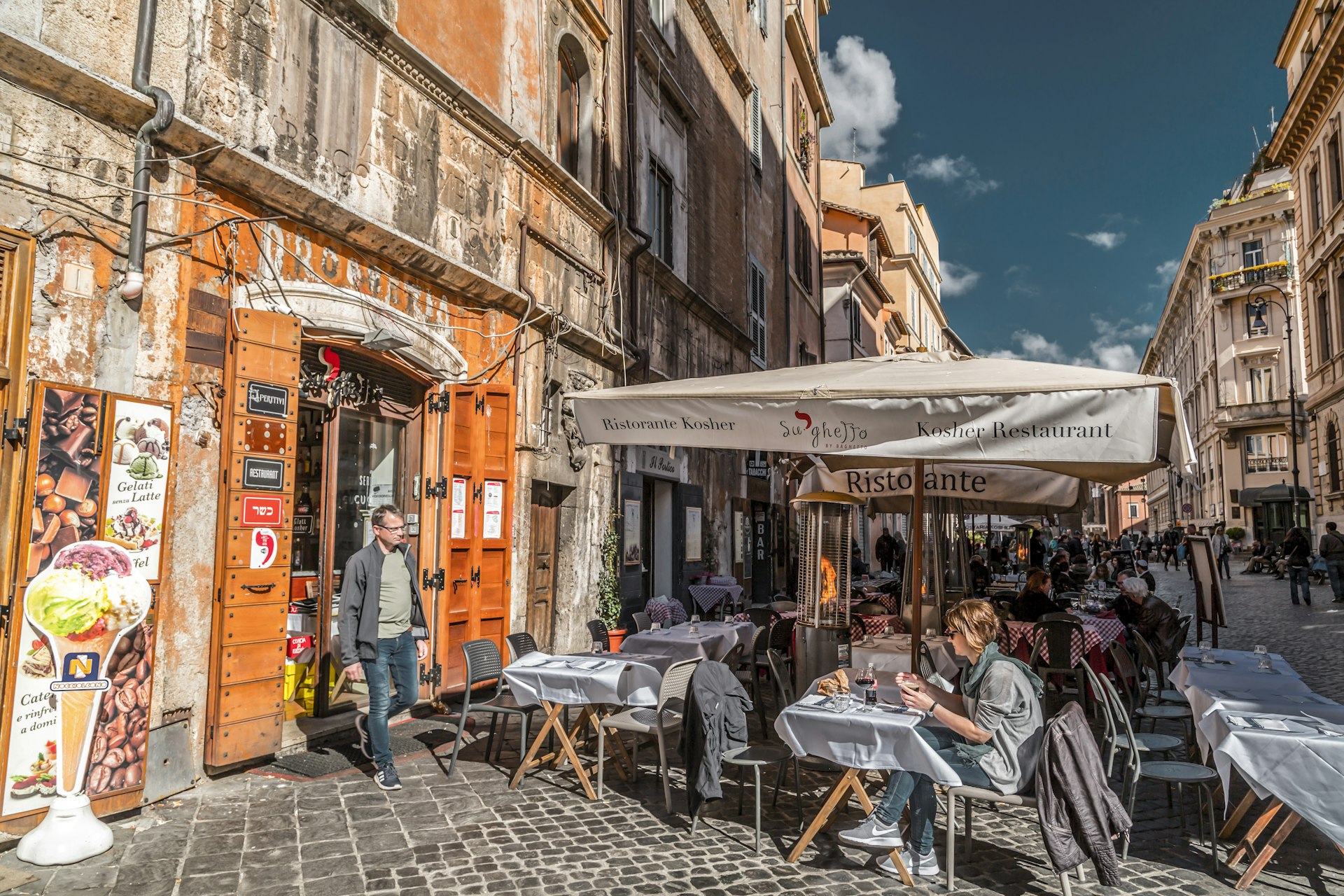 People eating al fresco on a cobbled street in Rome's Jewish district