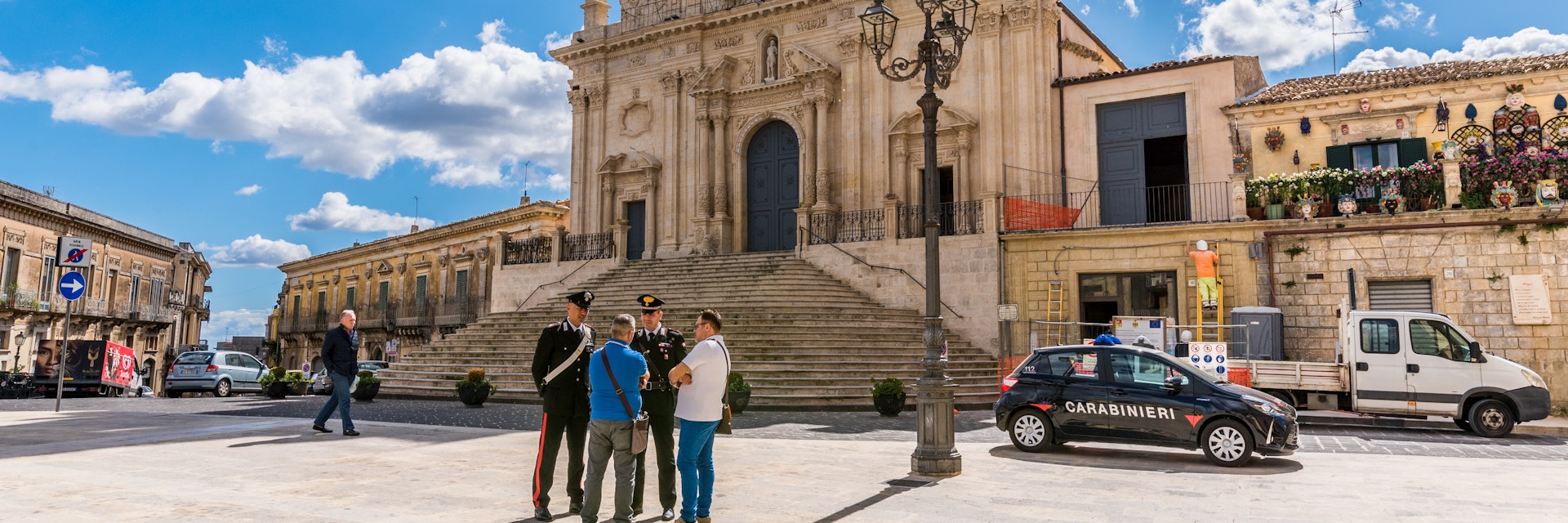 Palazzolo Acreide/ Syracuse Sicily/ Italy - october 04 2019: Two Carabinieri speak and give information to some tourists, on the steps in front of the cathedral of Palazzolo Acreide
1181168446
shops, attraction, baroque, bell tower, building, columns, cops, dome, exterior, flight of steps, heritage, historic, outdoor, police, style, temple, tourists, upright, windows, cars, police man, lamp, palazzolo, clouds, benemerita, square