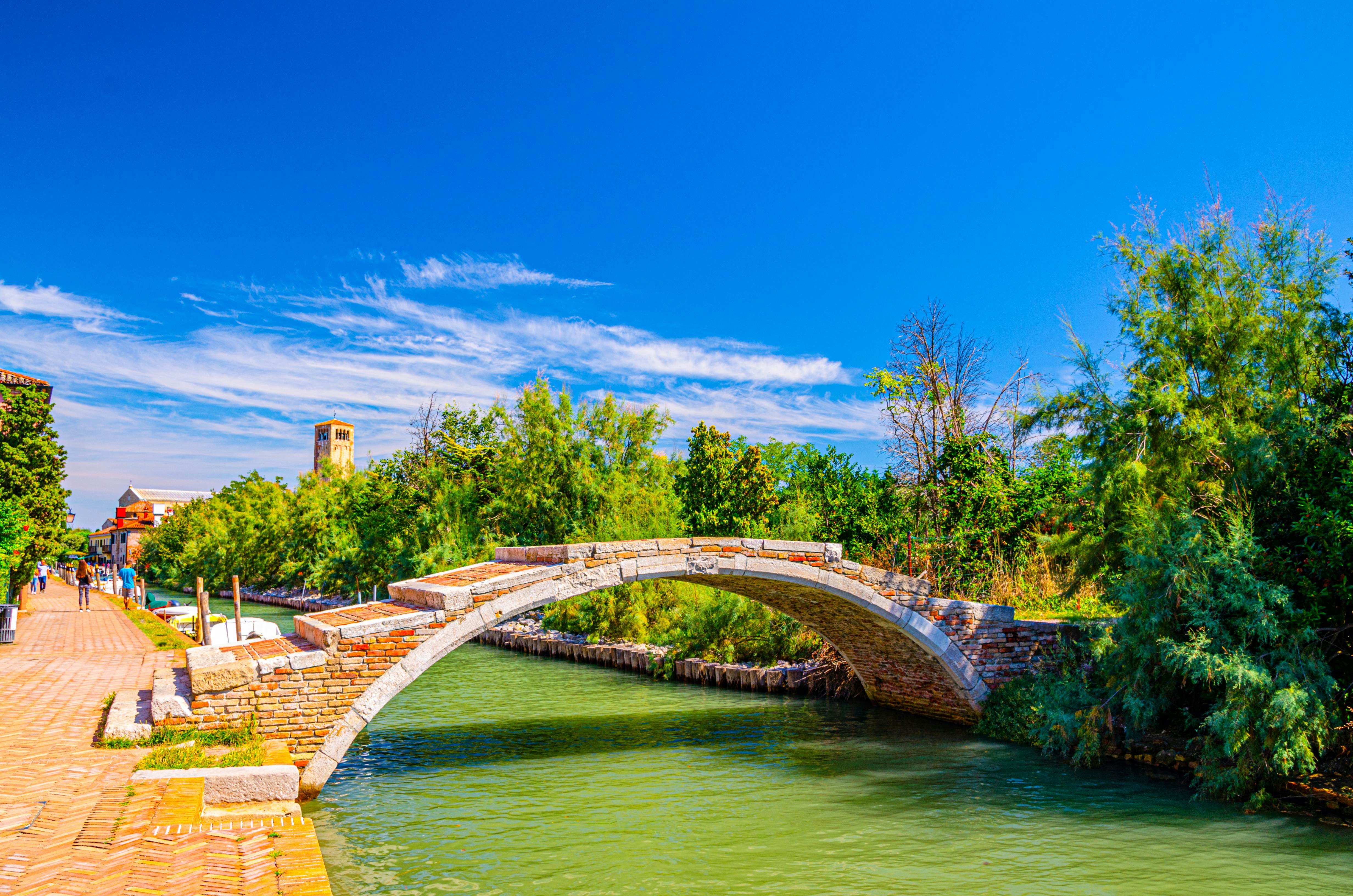 Stone Devil bridge across water canal on Torcello island, embankment promenade along water canal, green trees, tower and blue sky background. Venetian Lagoon, Veneto Region, Northern Italy.
1224140496
region, italia, populated, sparsely
