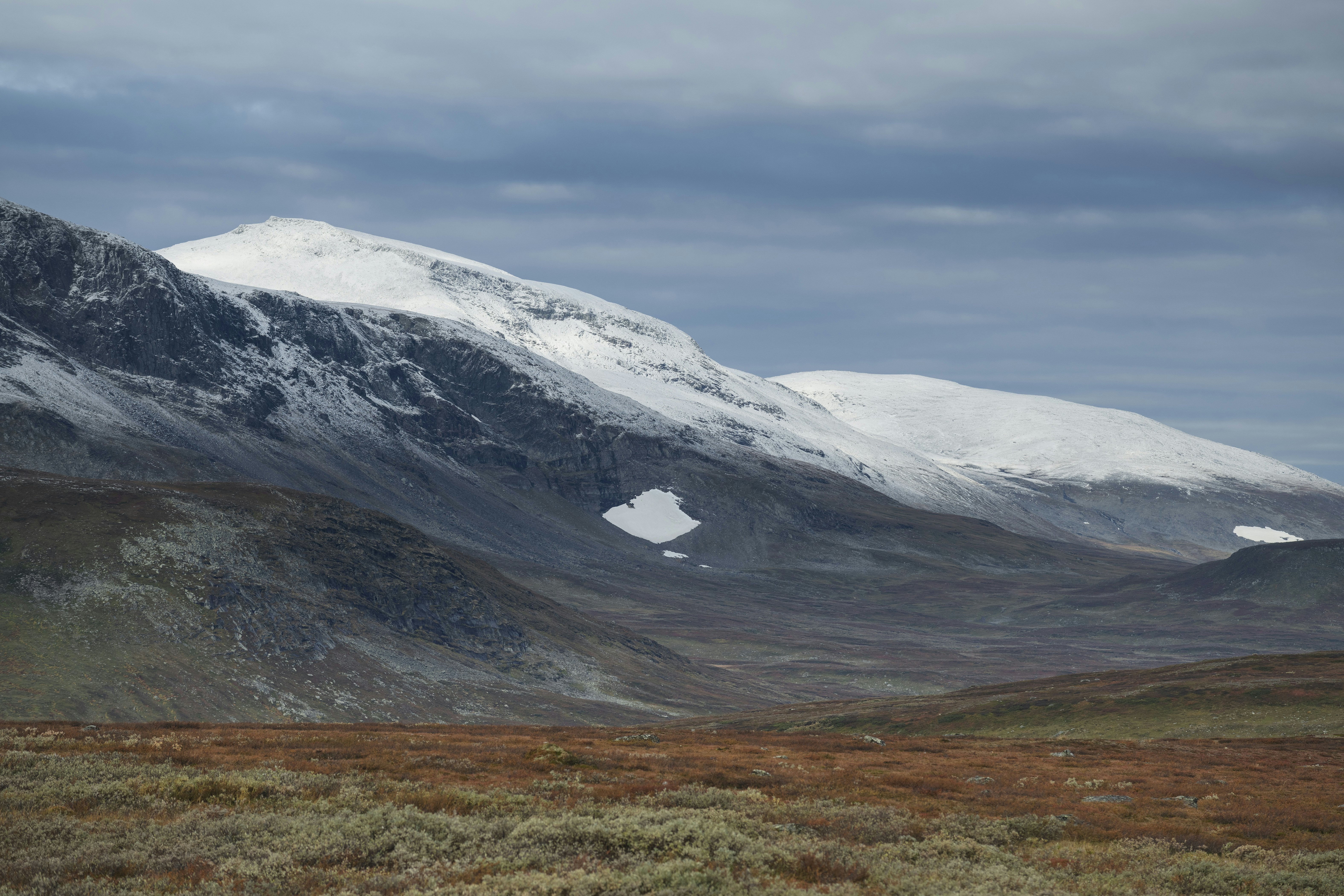 Dusting of autumn snow covers Ammarfjället mountains in Vindelfjällen nature reserve from Kungsleden Trail, Lapland, Sweden.