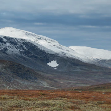 Dusting of autumn snow covers Ammarfjället mountains in Vindelfjällen nature reserve from Kungsleden Trail, Lapland, Sweden.