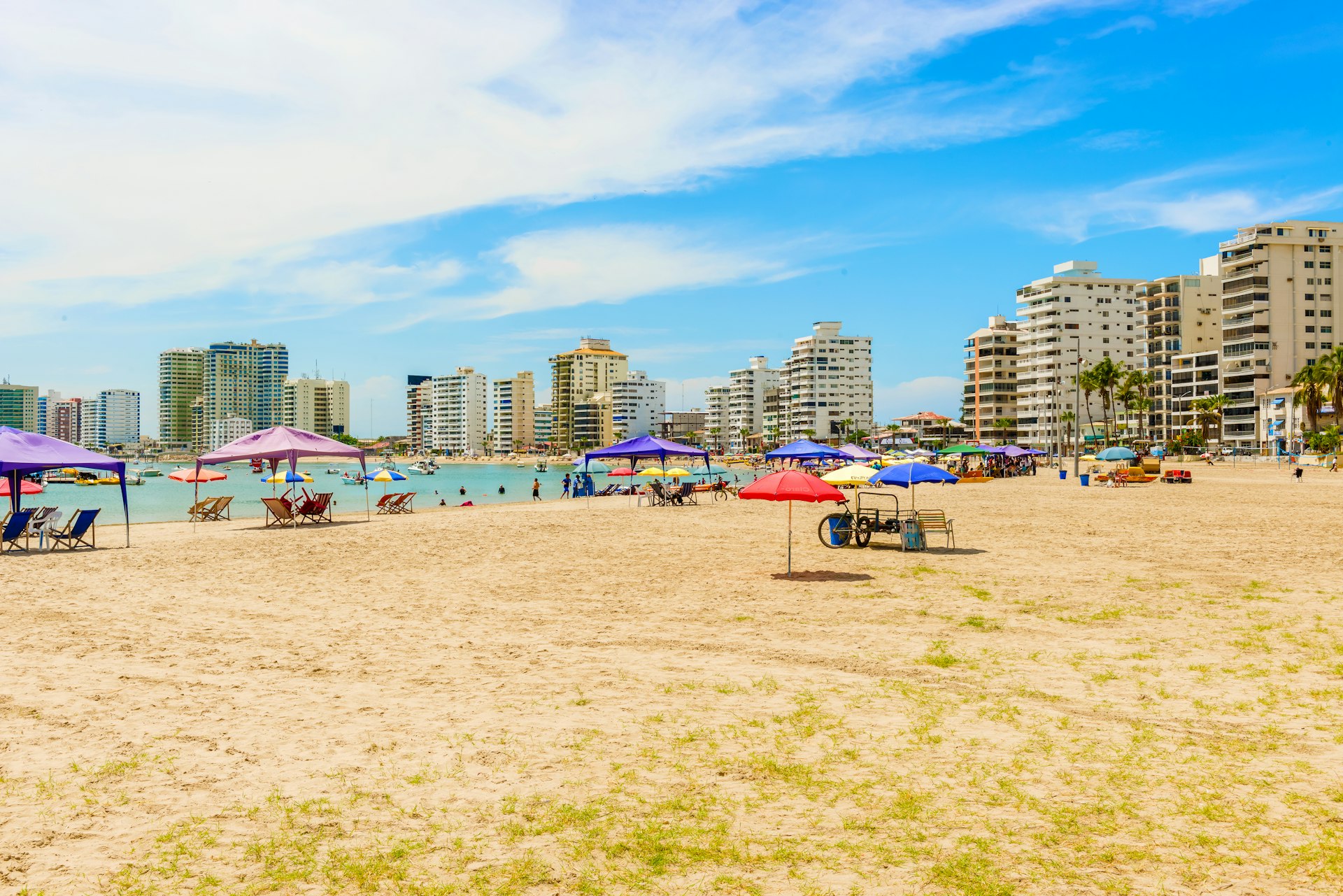 A city beach backed by apartment blocks and with many loungers and seats under gazebos
