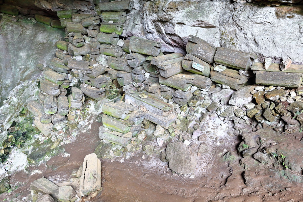 More than 100 wooden coffins stacked at the lichen-lined entrance hall of Lumiang Burial Cave.
