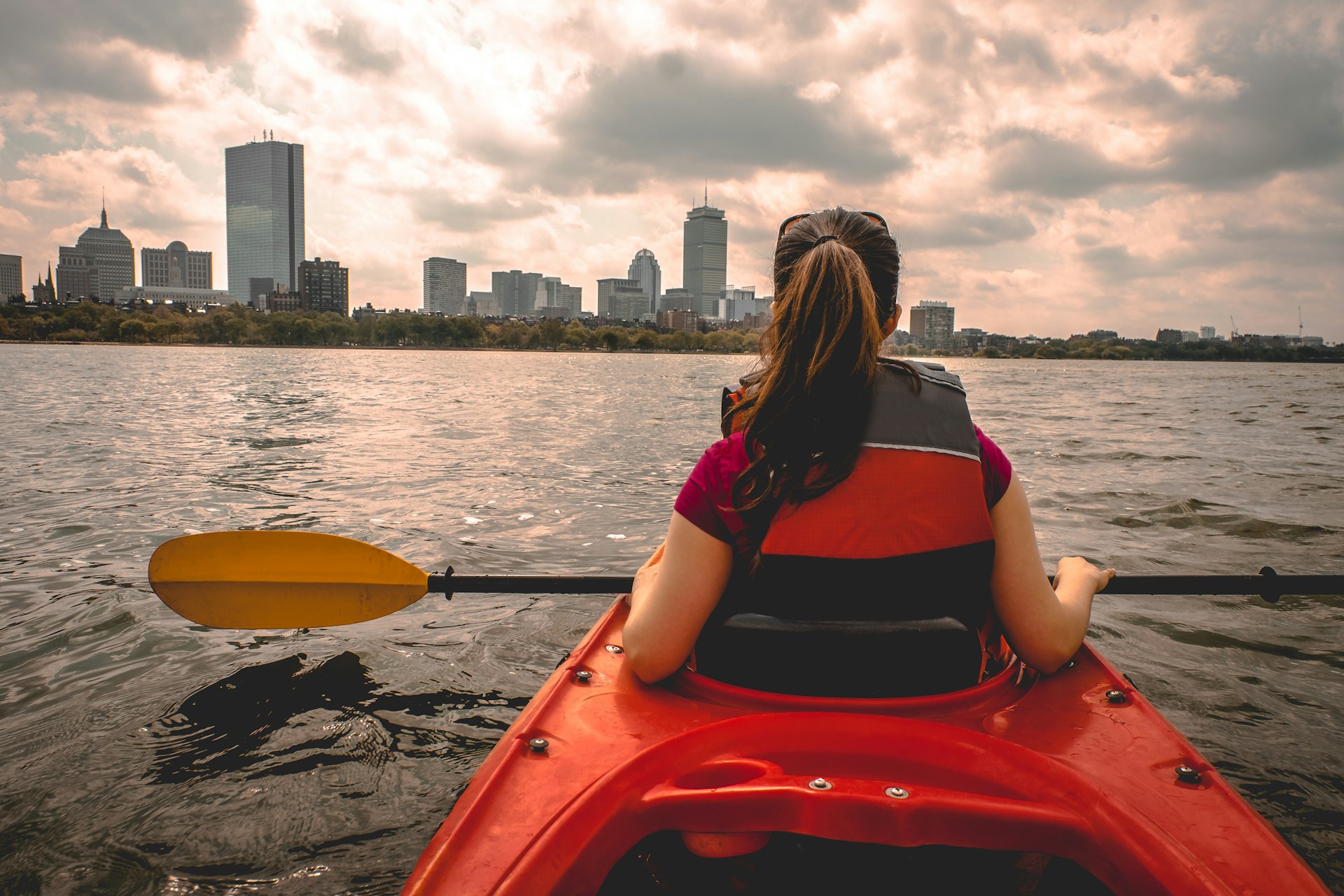 A teen in a red kayak floats along a river