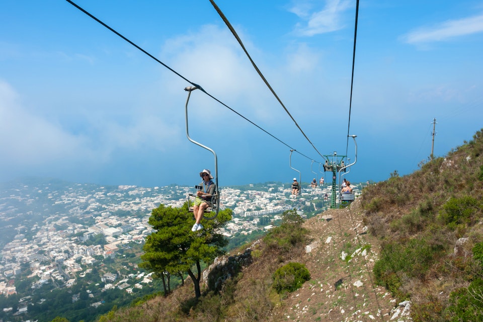 July 29, 2018: People riding up the mountain chair lift in Capri.
1158732217
above, adventure, aerial, amalfi, anacapri, cable, cableway, campania, capri, car, chair, chairlift, city, destination, europe, funicular, height, high, island, italian, italy, landscape, lift, mediterranean, monte, mount, mountain, naples, nature, people, sea, sky, solaro, summer, top, tour, tourism, tourist, touristic, town, transport, transportation, travel, trip, vacation, view, way