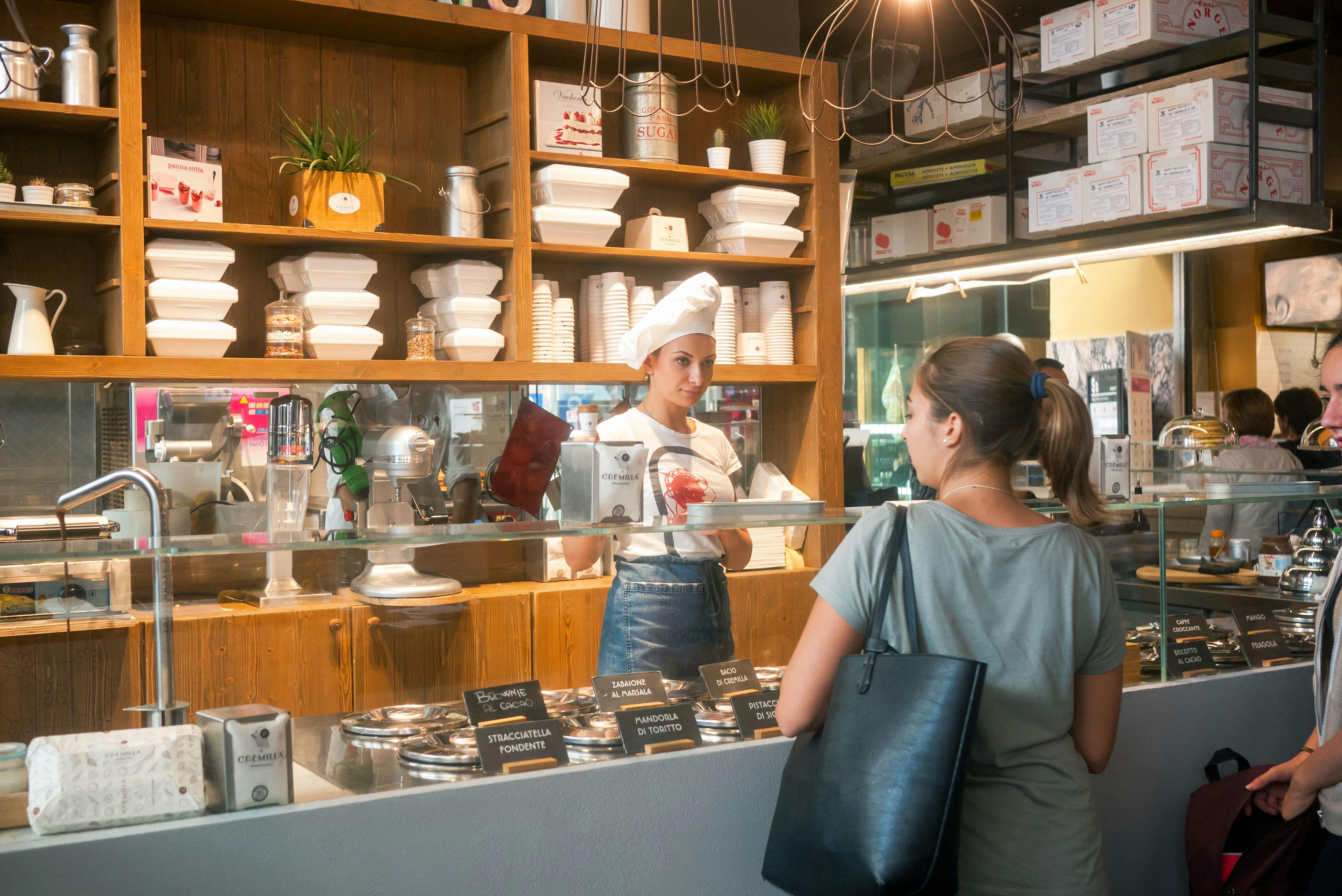 Woman serving a customer at the Gelateria at Mercato Centrale Termini Station.