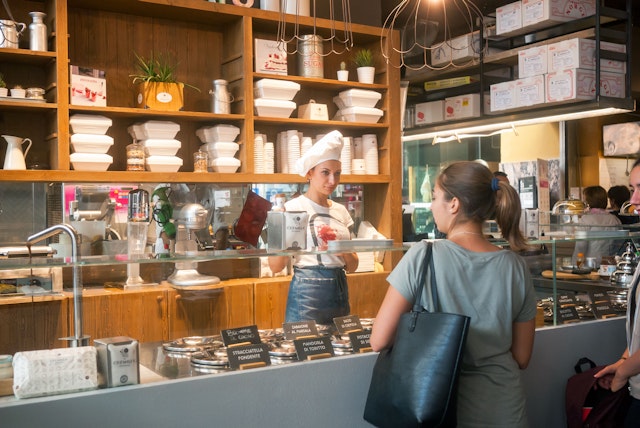 Woman serving a customer at the Gelateria at Mercato Centrale Termini Station.