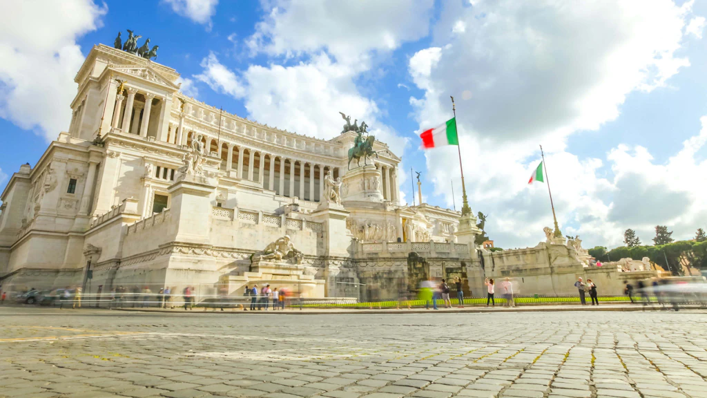Vittoriano, Rome A massive white building surrounded by many statues with Italian flags flying outside