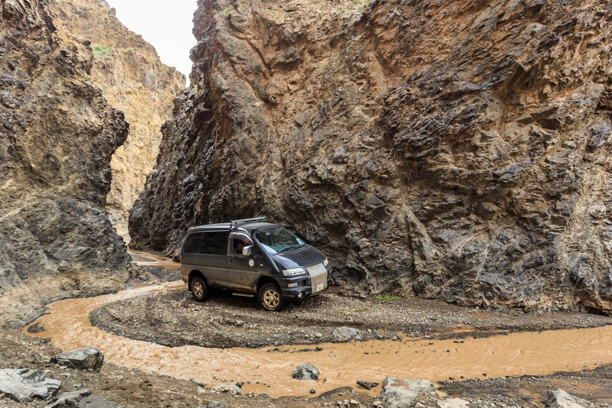 Off road vehicle travels an adventurous alternative and rocky route through Dugany Am, a spectacular narrow gorge in the mountains of the Gobi, Gurvan Saikhan National Park, Mongolia.