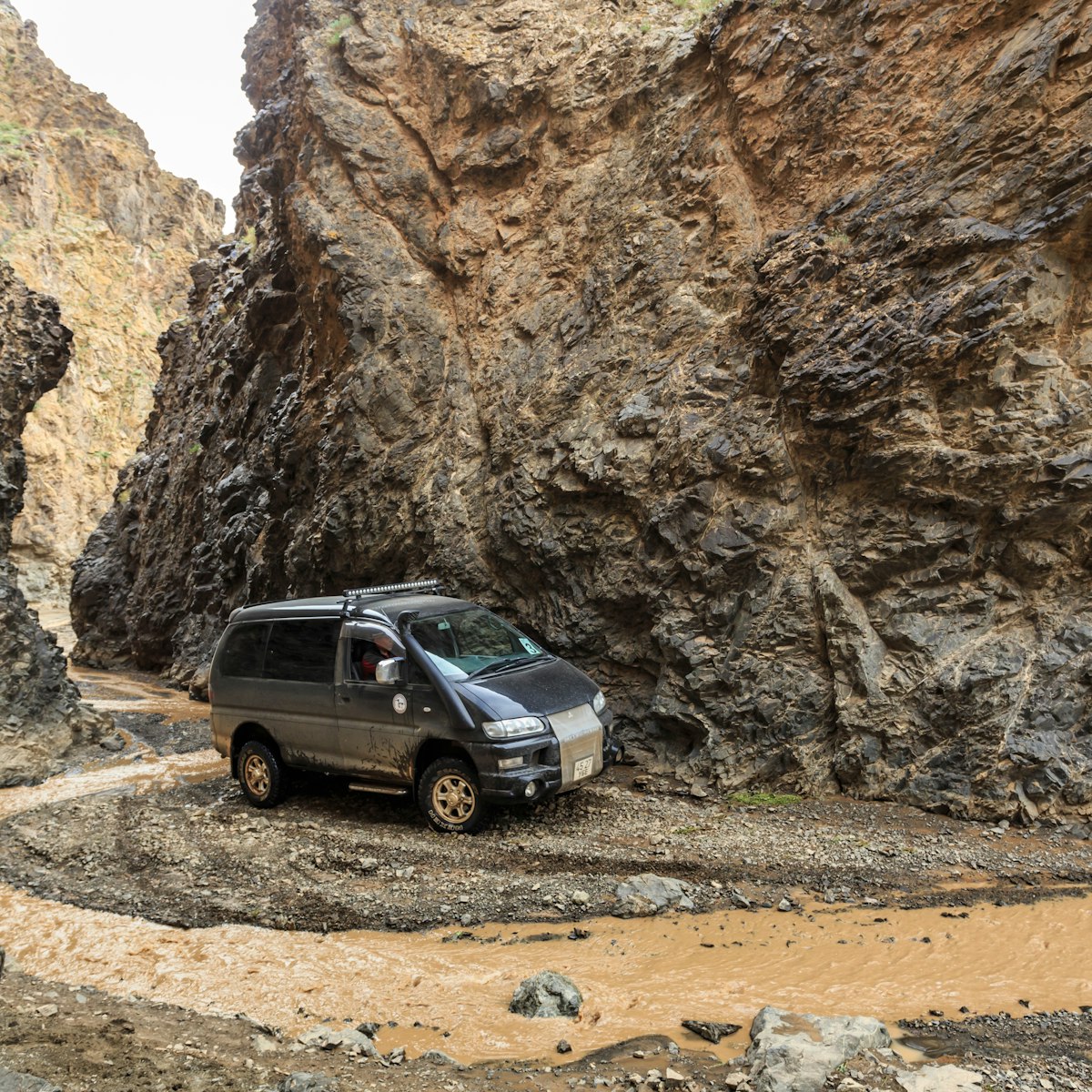 Off road vehicle travels an adventurous alternative and rocky route through Dugany Am, a spectacular narrow gorge in the mountains of the Gobi, Gurvan Saikhan National Park, Mongolia.
