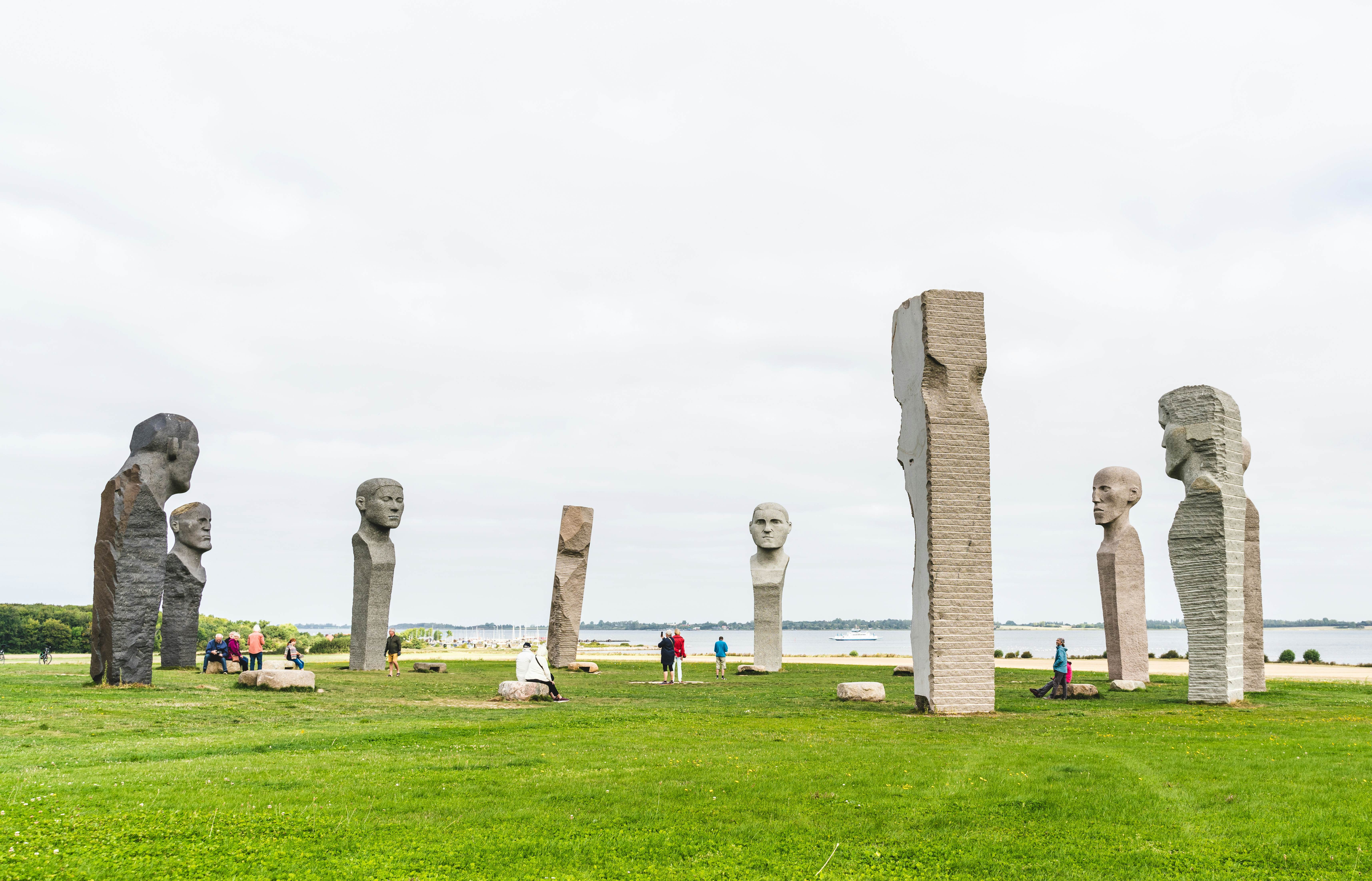 Tourists visiting Dodekalitten, the site of large stone statues on a summers day in Denmark.