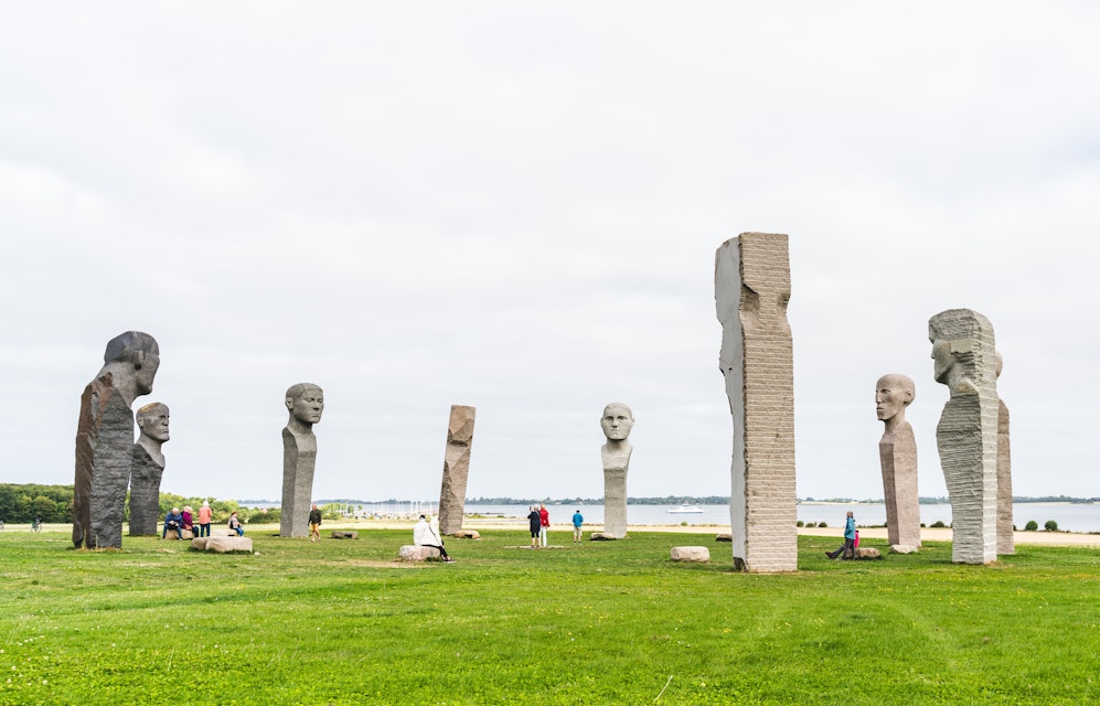 Tourists visiting Dodekalitten, the site of large stone statues on a summers day in Denmark.