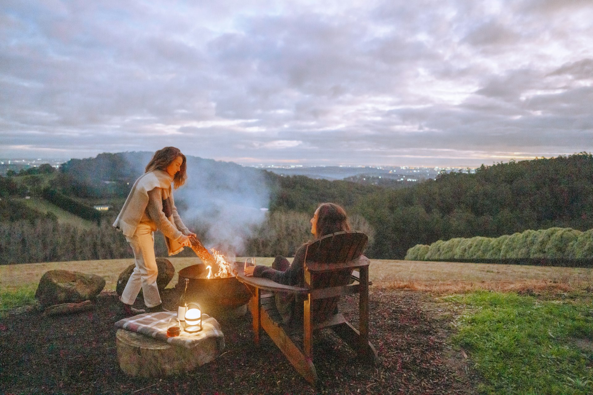 Two women stoking an outdoor fire at Larnook - off-grid accommodation in Victoria