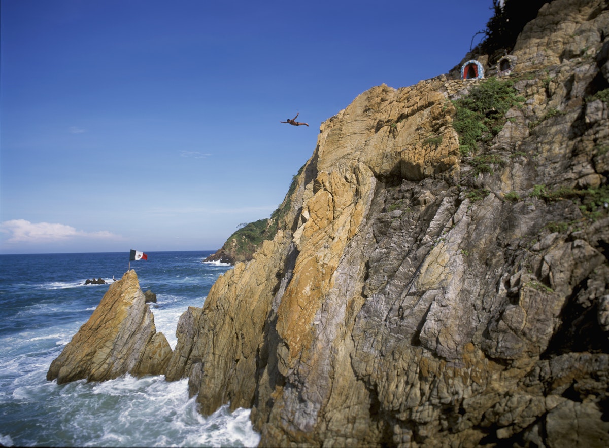 Mexico: Acapulco: A La Quebrada cliff diver leaps into the Pacific Ocean, along the Mexican Riviera